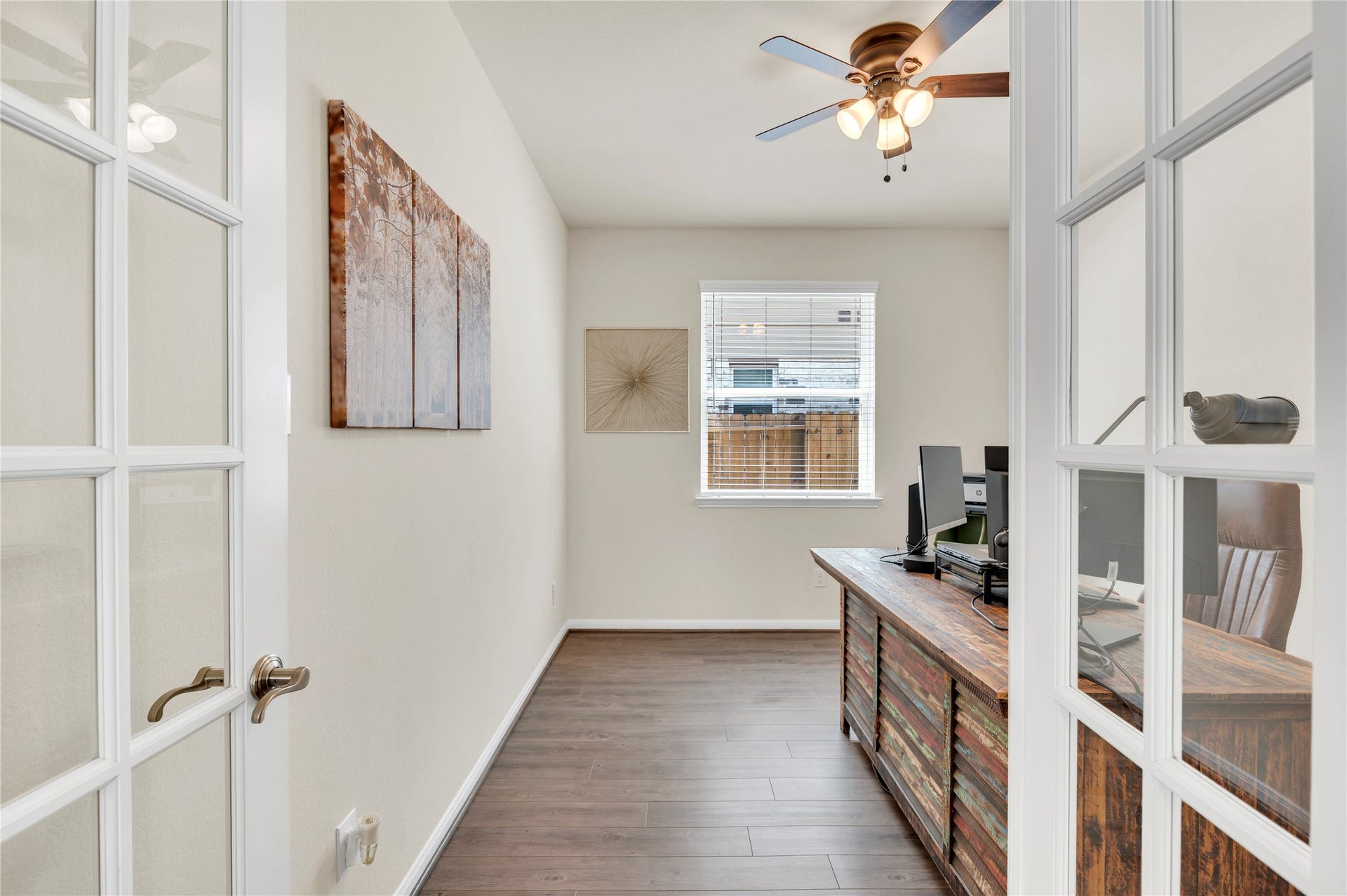 1849 Kenley Way, Alvin, TX 77511 Charming home office with glass French doors, rich wood flooring, and ample natural light from a large window, creating an inviting workspace. This room also has a closet for additional storage or a 4th bedroom.