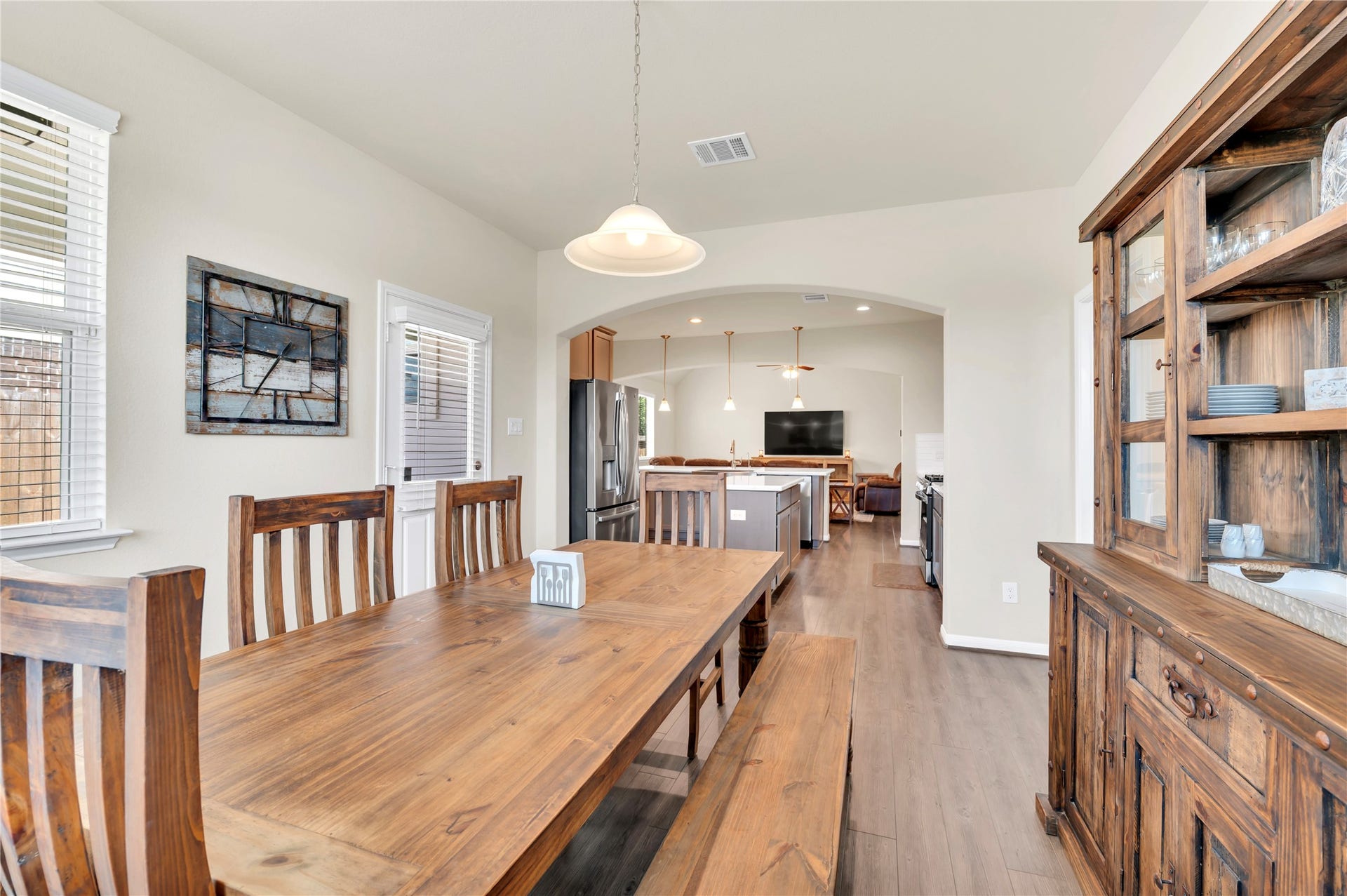 1849 Kenley Way, Alvin, TX 77511 Spacious dining area with elegant wood furniture leads seamlessly into a modern kitchen and cozy living space, perfect for gatherings.