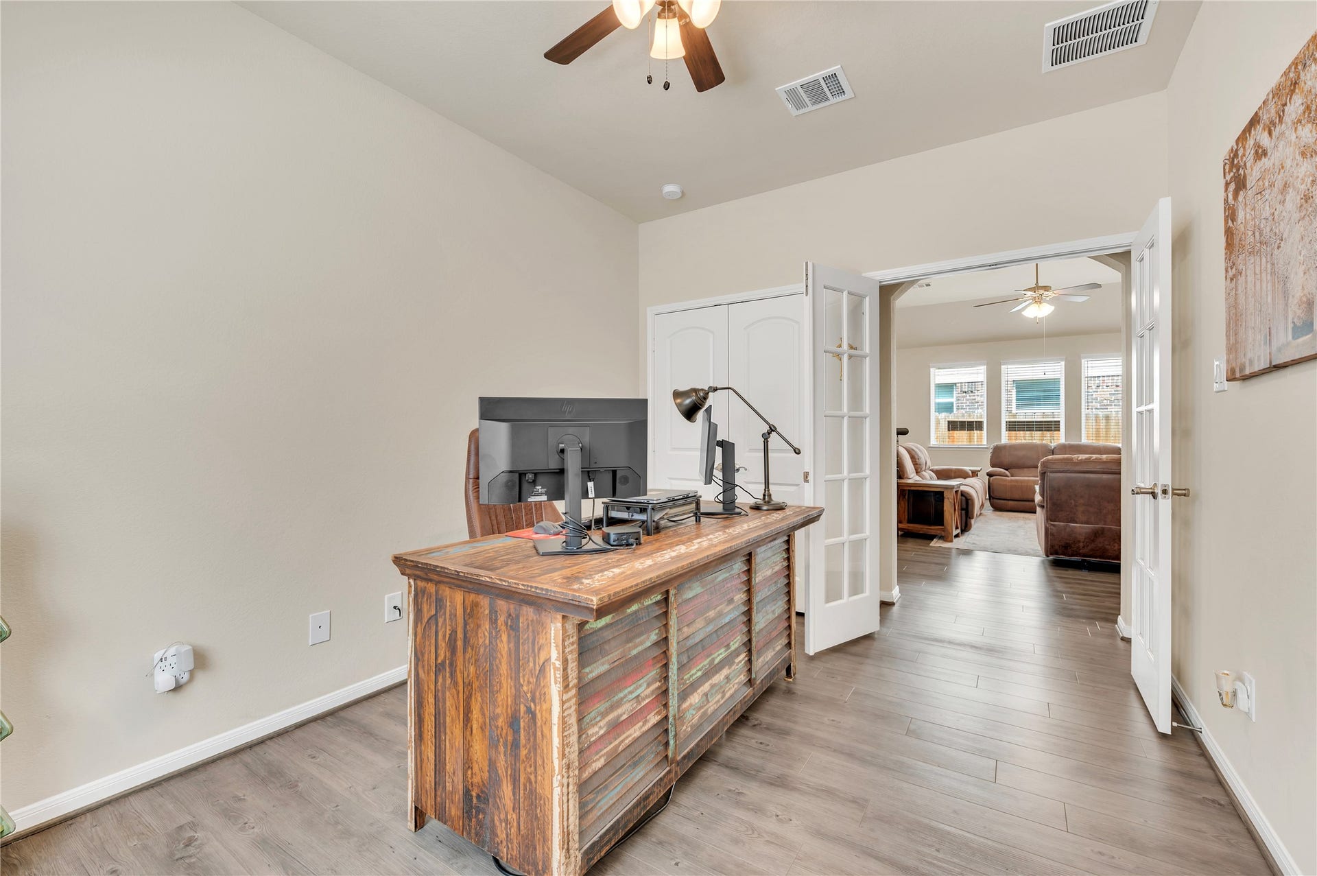 1849 Kenley Way, Alvin, TX 77511 Charming home office with rustic desk, ceiling fan, and French doors leading to a cozy living area with ample natural light.