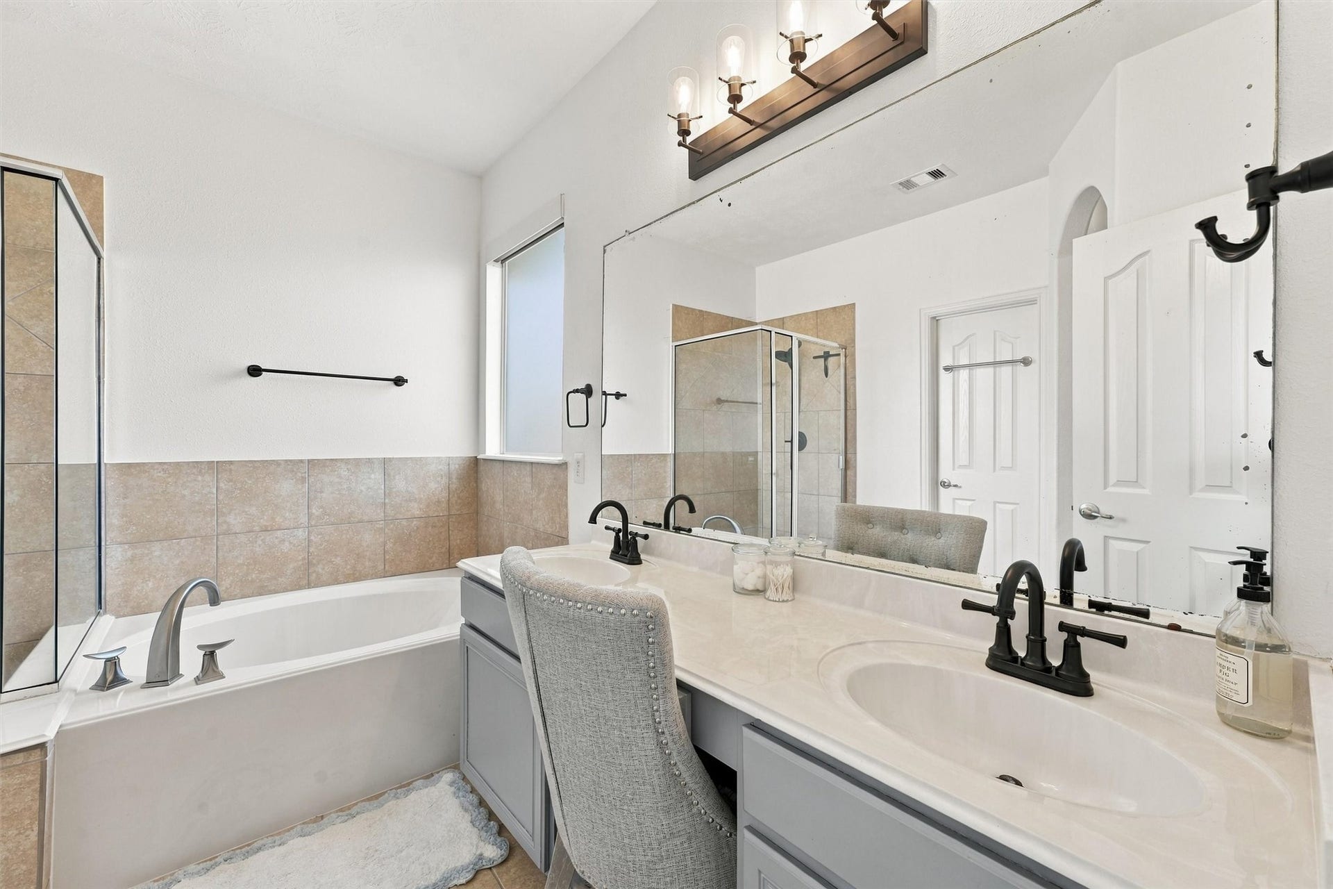 Primary bathroom with dual sinks, soaking tub, and separate standing shower.