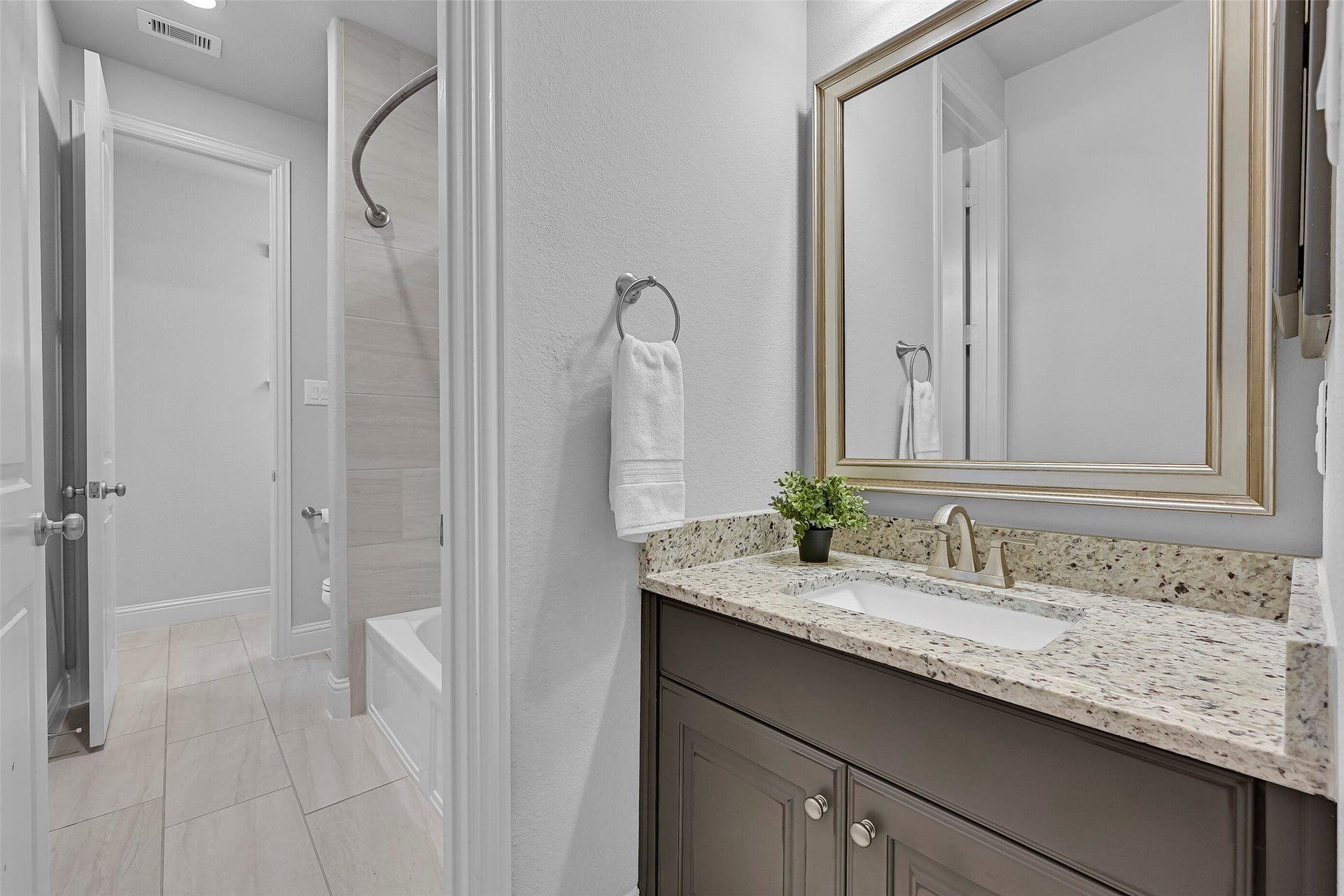 Connecting the secondary bedrooms, this well-appointed Jack & Jill bath features a granite vanity, framed mirror, upgraded cabinetry, and durable tile flooring. The thoughtful layout allows the vanity area to remain accessible while the bathing area is in use.