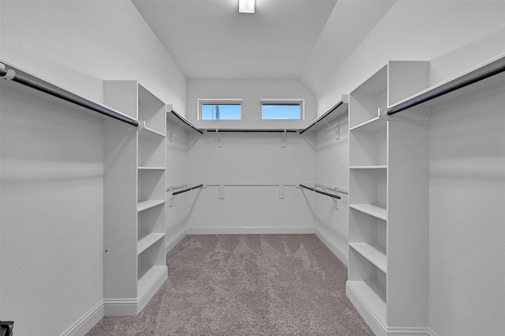 The enormous walk-in closet offers built-in shelving, multiple hanging areas, and abundant storage for every season. High ceilings and transom windows provide natural light, creating an organized and functional extension of the primary suite.
