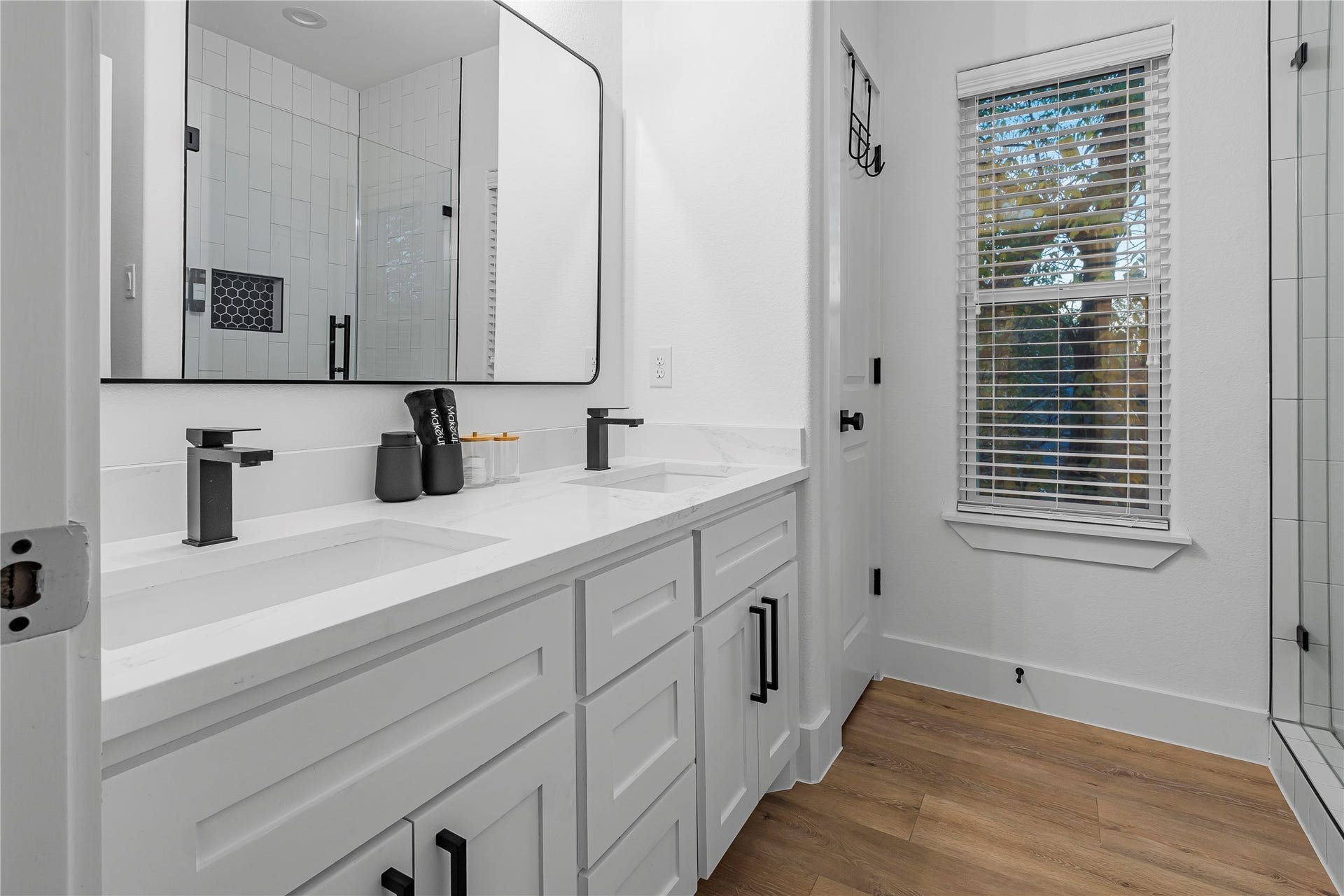 7107 Foster Street, #B, Houston, TX 77021 Elegant bathroom with a dual-sink vanity, sleek black fixtures, and a large mirror. Abundant natural light filters through the window, complementing the stylish tile shower.