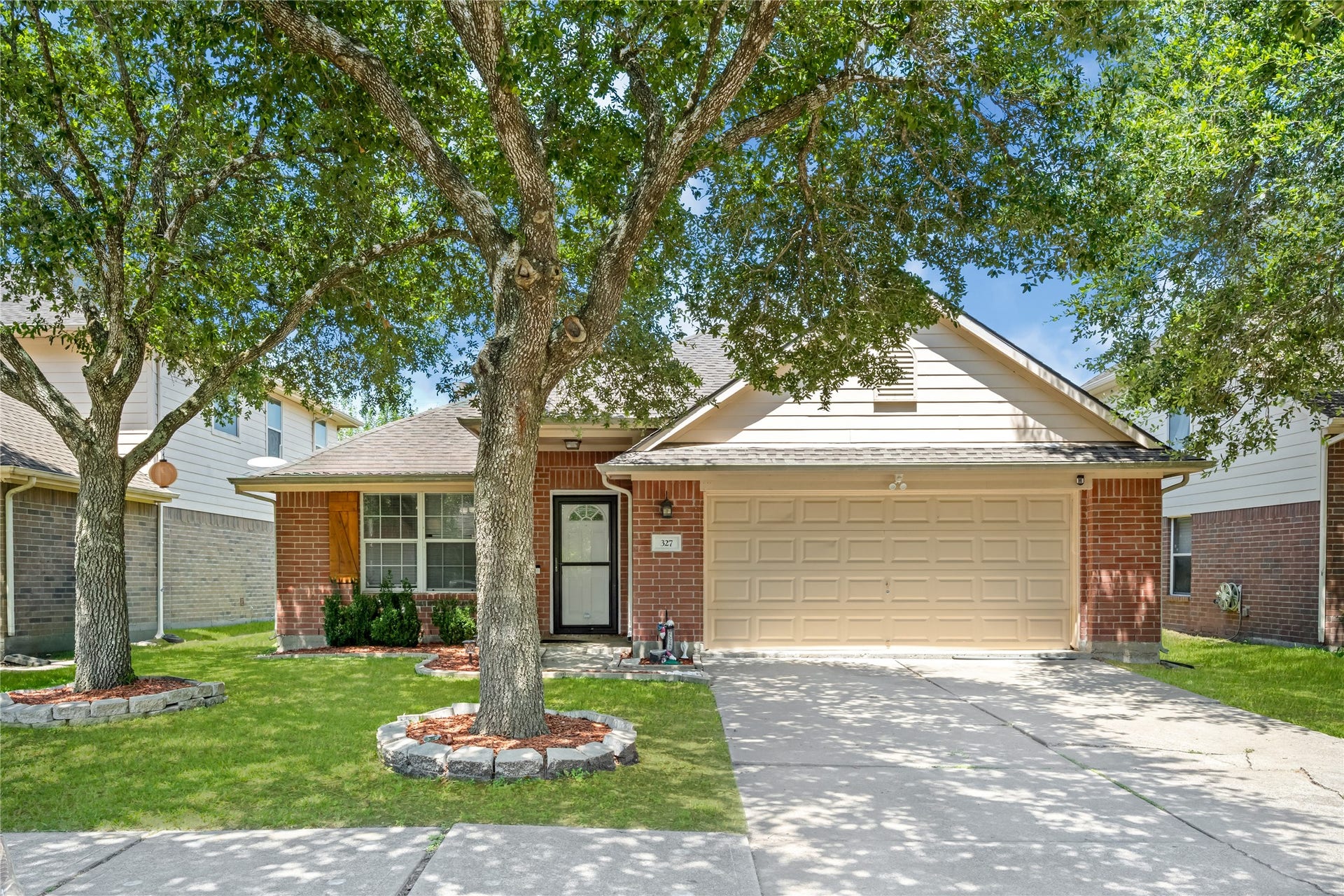 327 Mammoth Springs Lane, Dickinson, TX 77539 Charming front exterior showcasing a manicured lawn, beautiful mature tree, and an attached two-car garage.