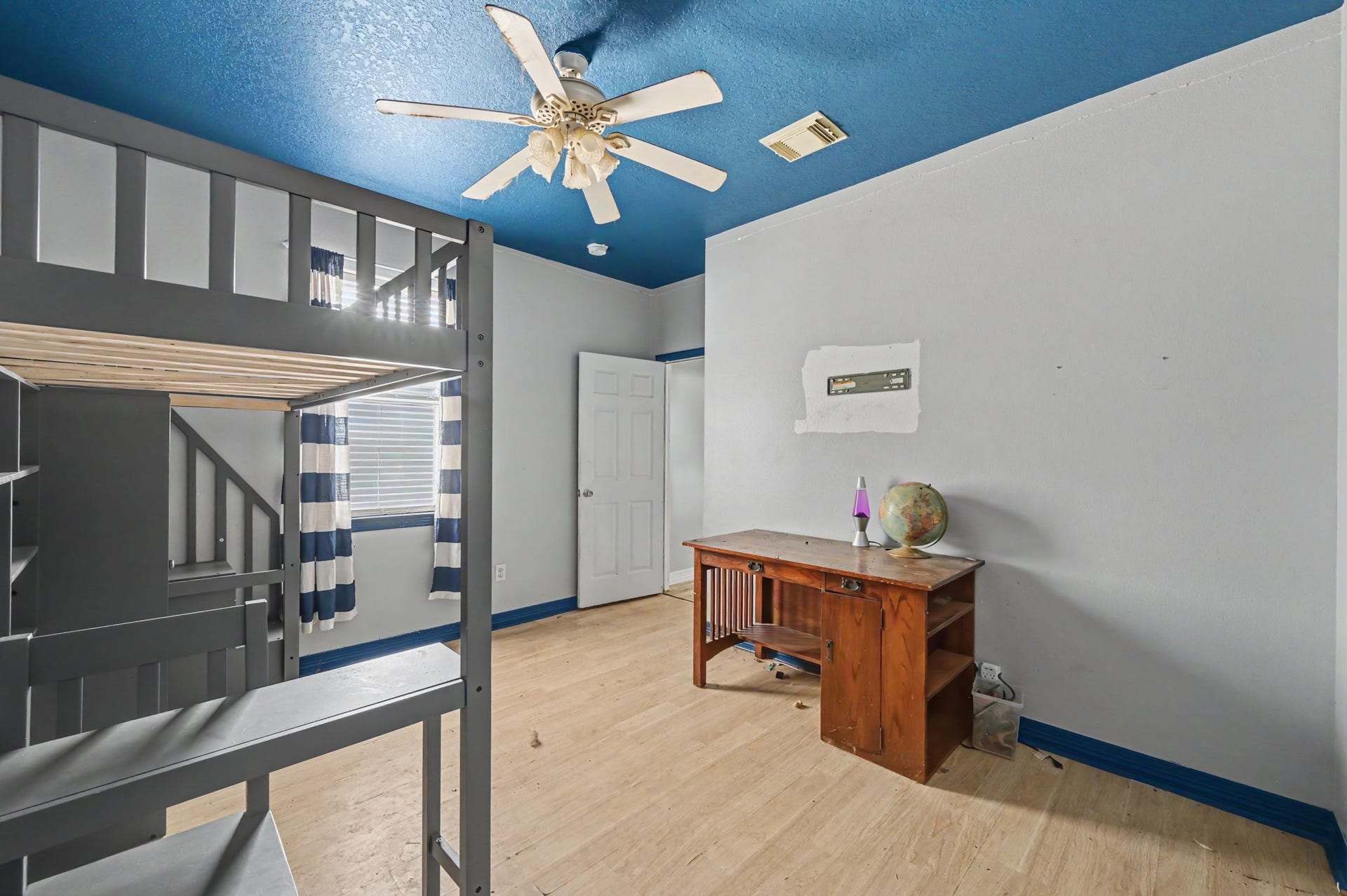 Another view of the secondary bedroom showcasing the unique blue ceiling, generous floor space, and versatile layout
