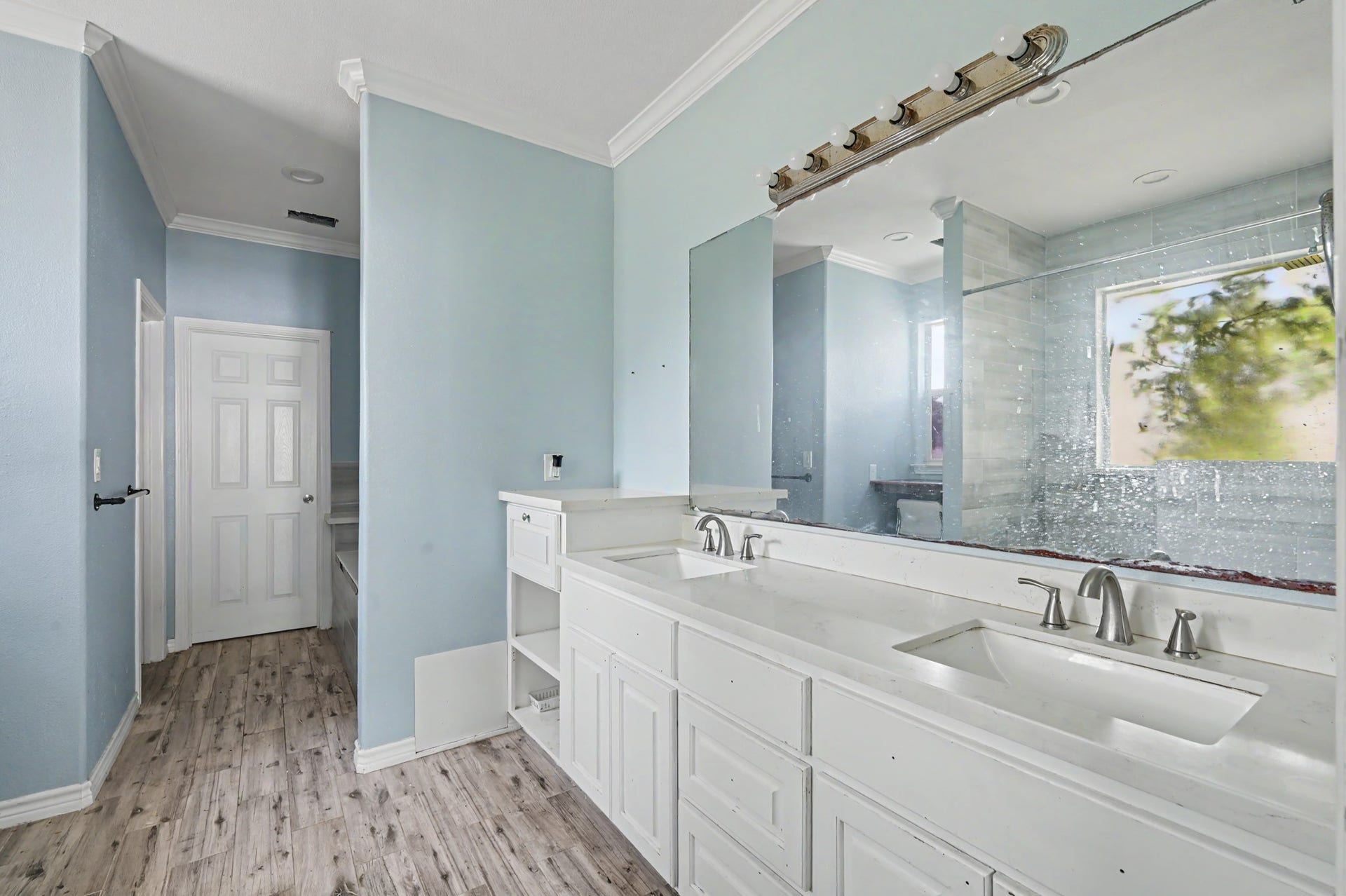 Bright primary bath with double vanity, abundant counter and cabinet space, large mirror, and walk-in shower.
