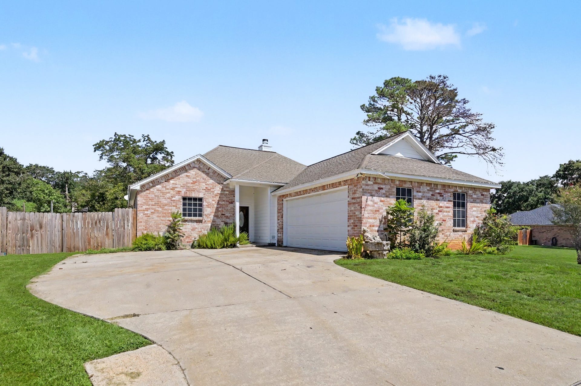Front exterior with spacious driveway, mature landscaping, and easy access to the backyard