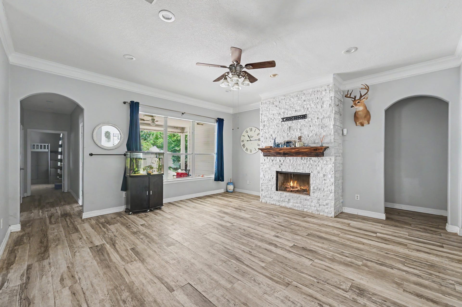 Open living room featuring a striking floor-to-ceiling stone fireplace with wood mantel.