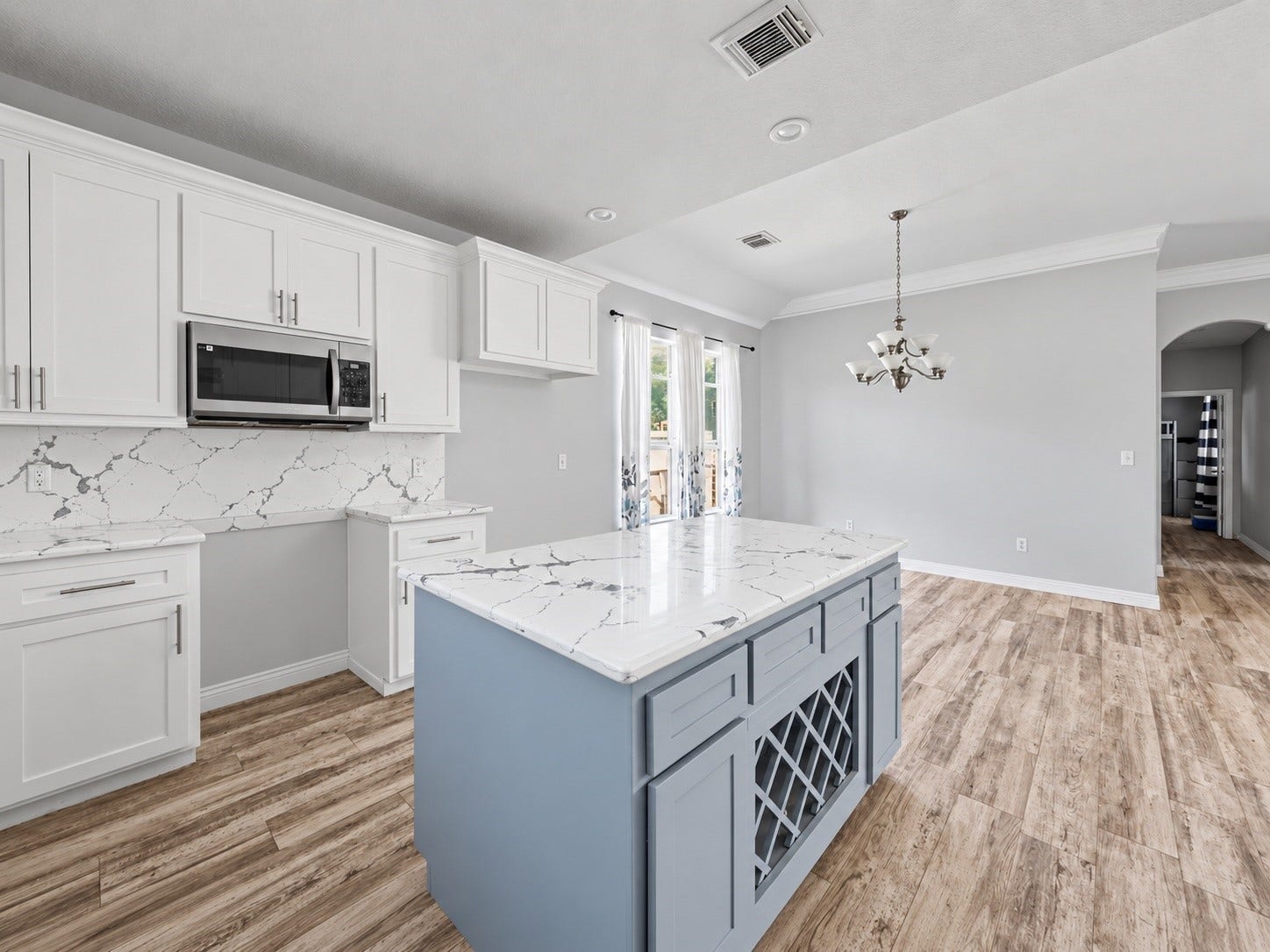 Another view of the beautifully updated kitchen showcasing the oversized island, decorative wine storage, and adjacent dining room. ***Digitally enhanced kitchen pictures - backsplash needs to be completed