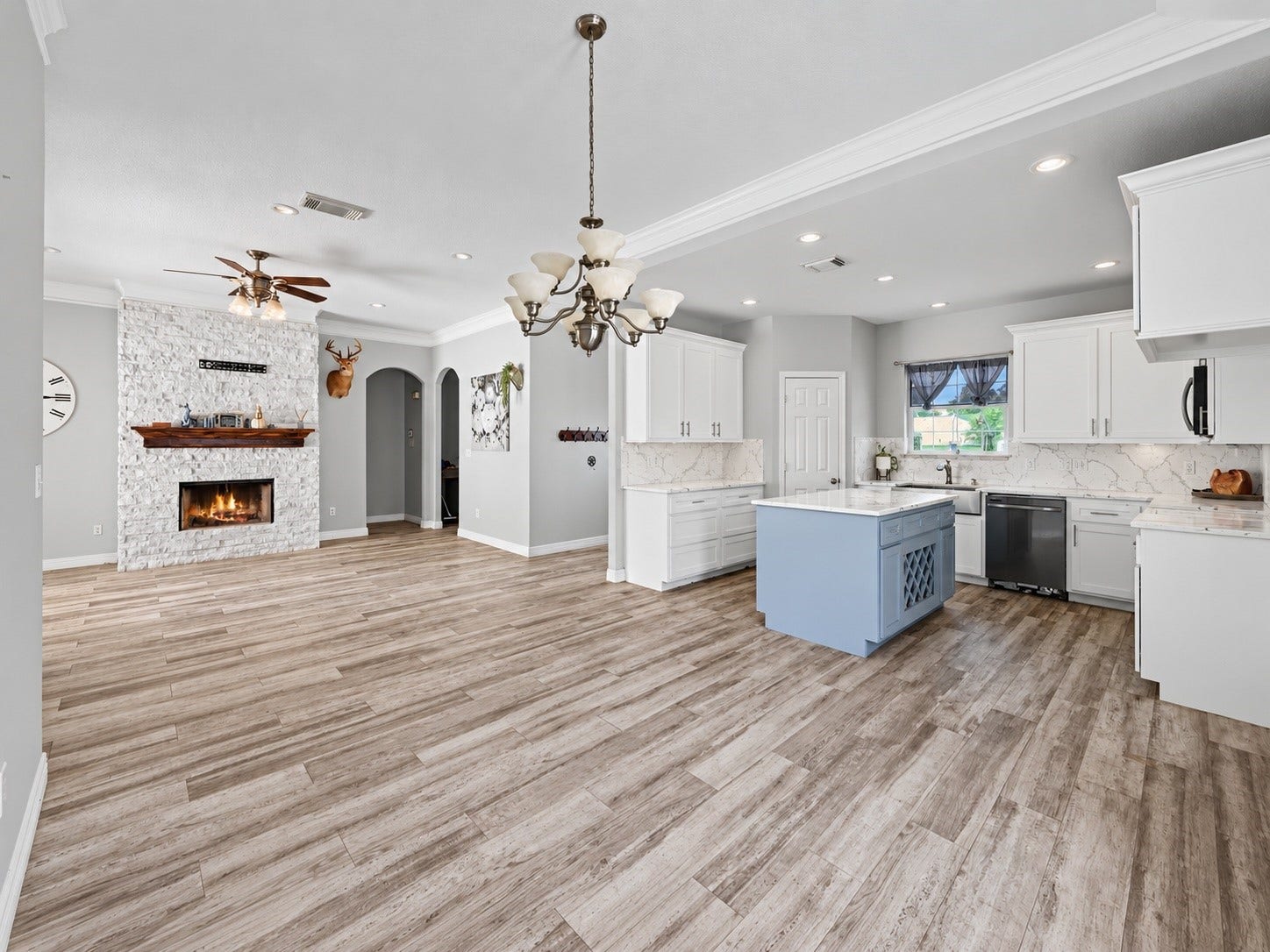 Open-concept kitchen, dining, and living area with new tile flooring and beautiful floor-to-ceiling stone fireplace. ***Digitally enhanced kitchen pictures - backsplash needs to be completed
