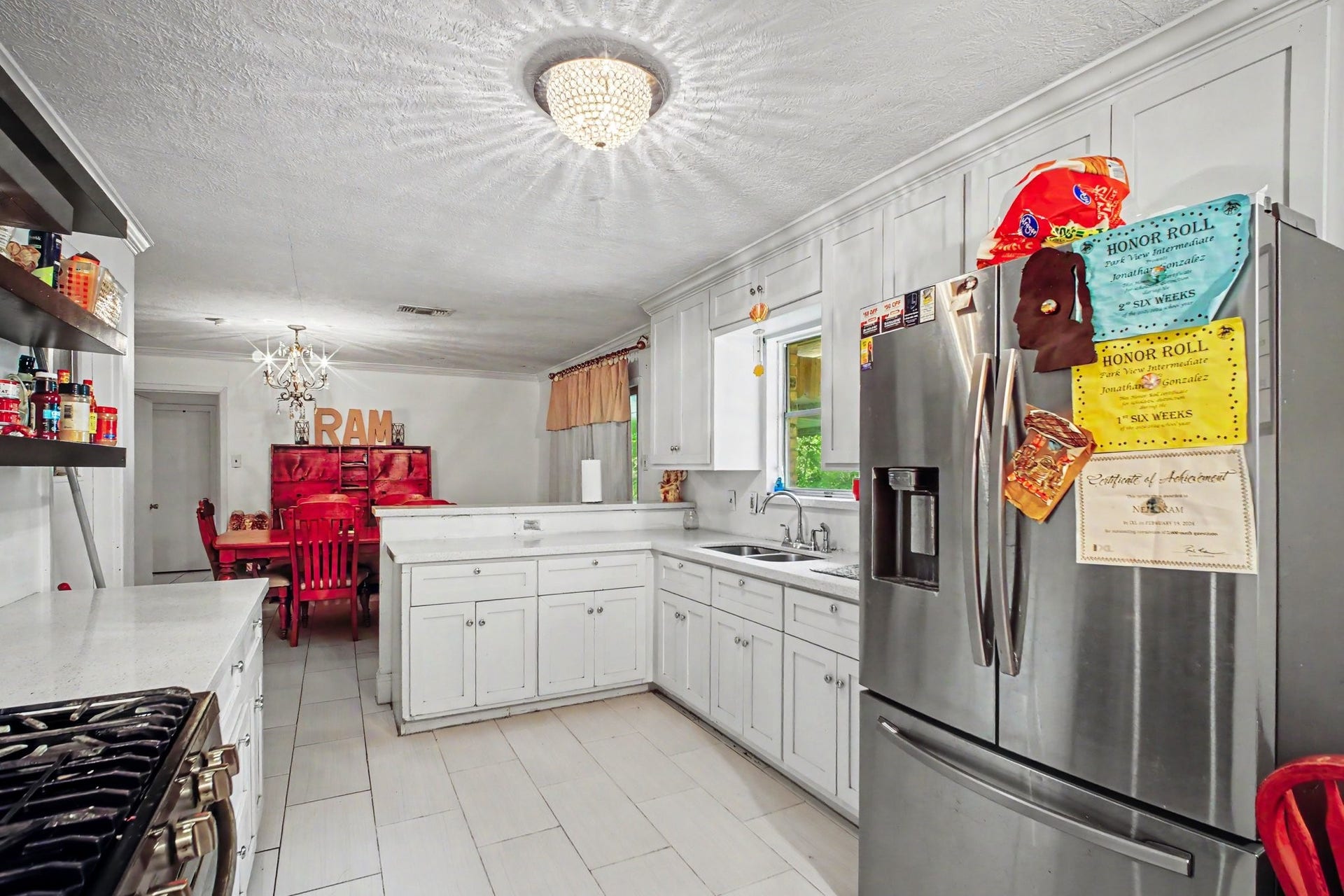 Close-up view of the kitchen counter prep spaces, storage cabinets, and stainless steel refrigerator.