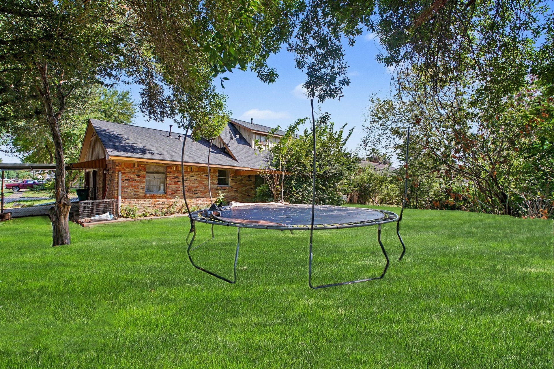Expansive backyard lawn area complete with recreational equipment set against open trees.