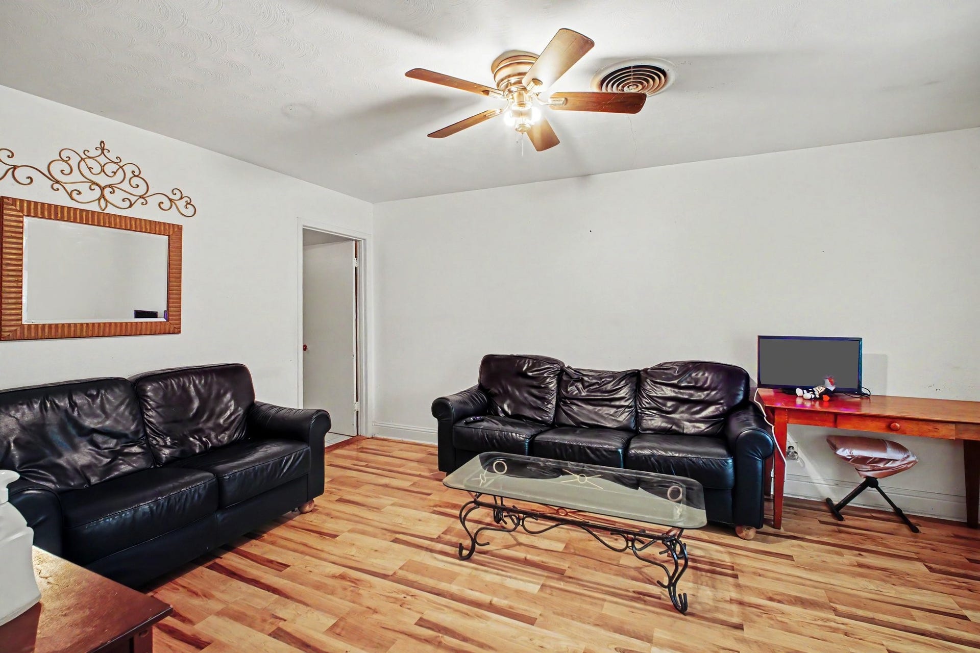 Inviting living area furnished with comfortable dark leather couches and warm wood flooring.