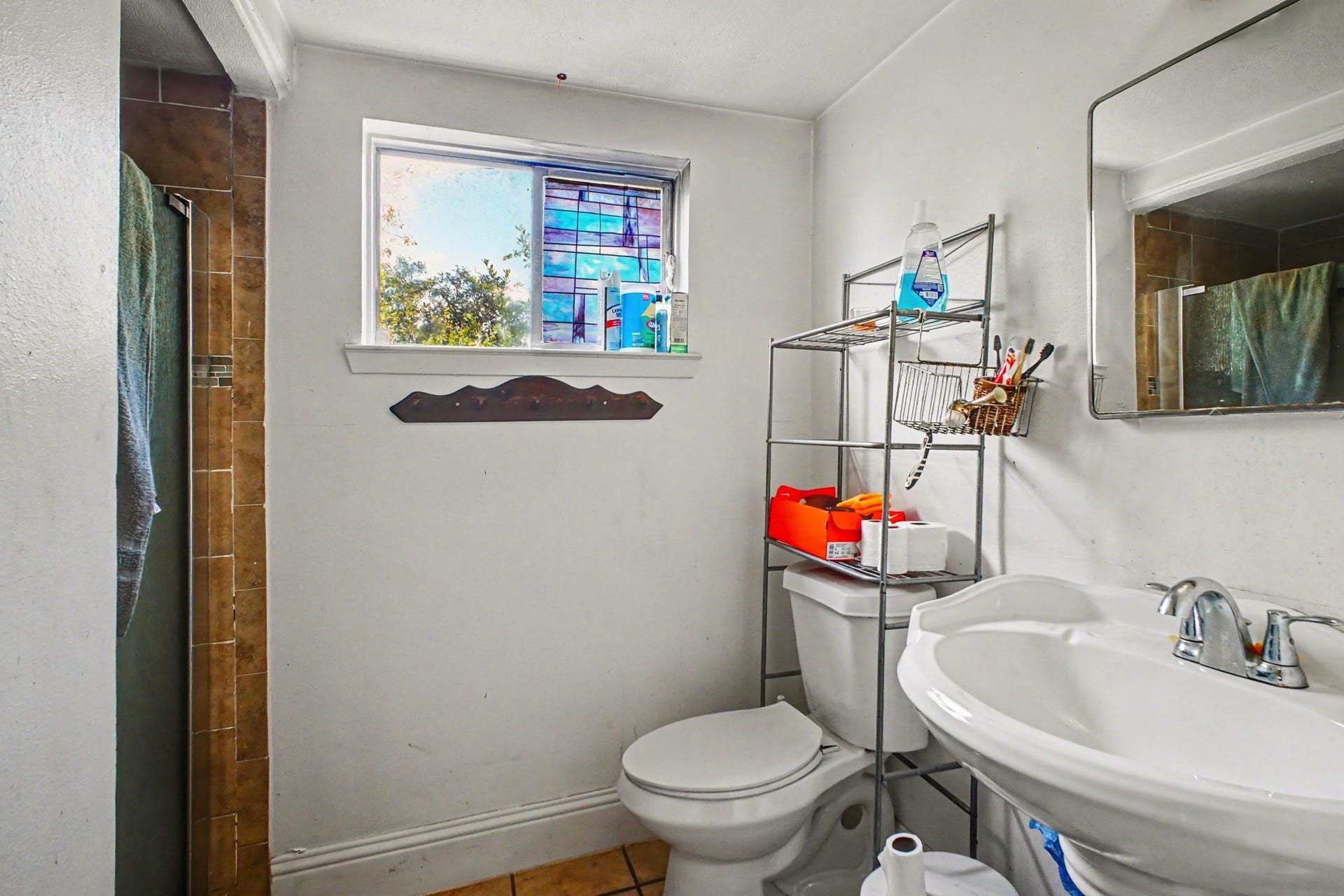 Well-lit bathroom space equipped with a compact vanity, mirror, and toilet.