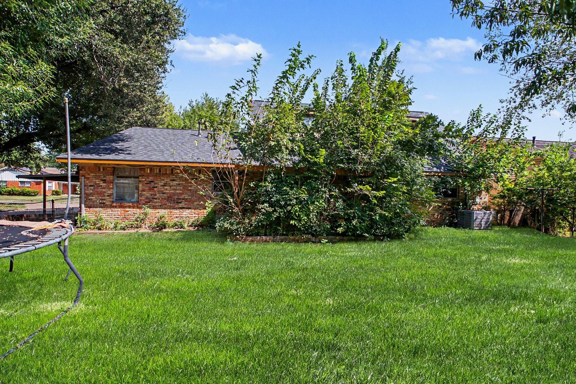 Charming street-level perspective of the front facade, mature landscaping, and sprawling yard space.