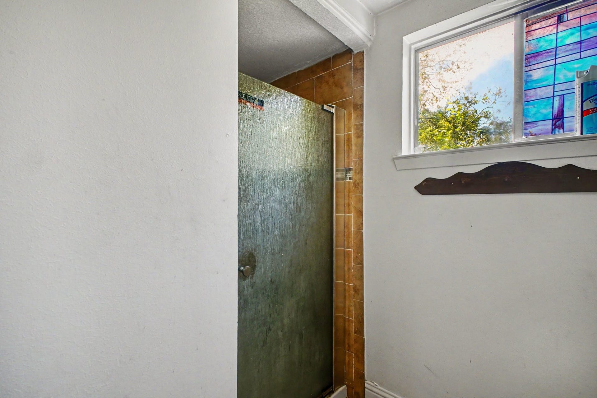 Functional bathroom area featuring a standing shower stall and decorative accent window.
