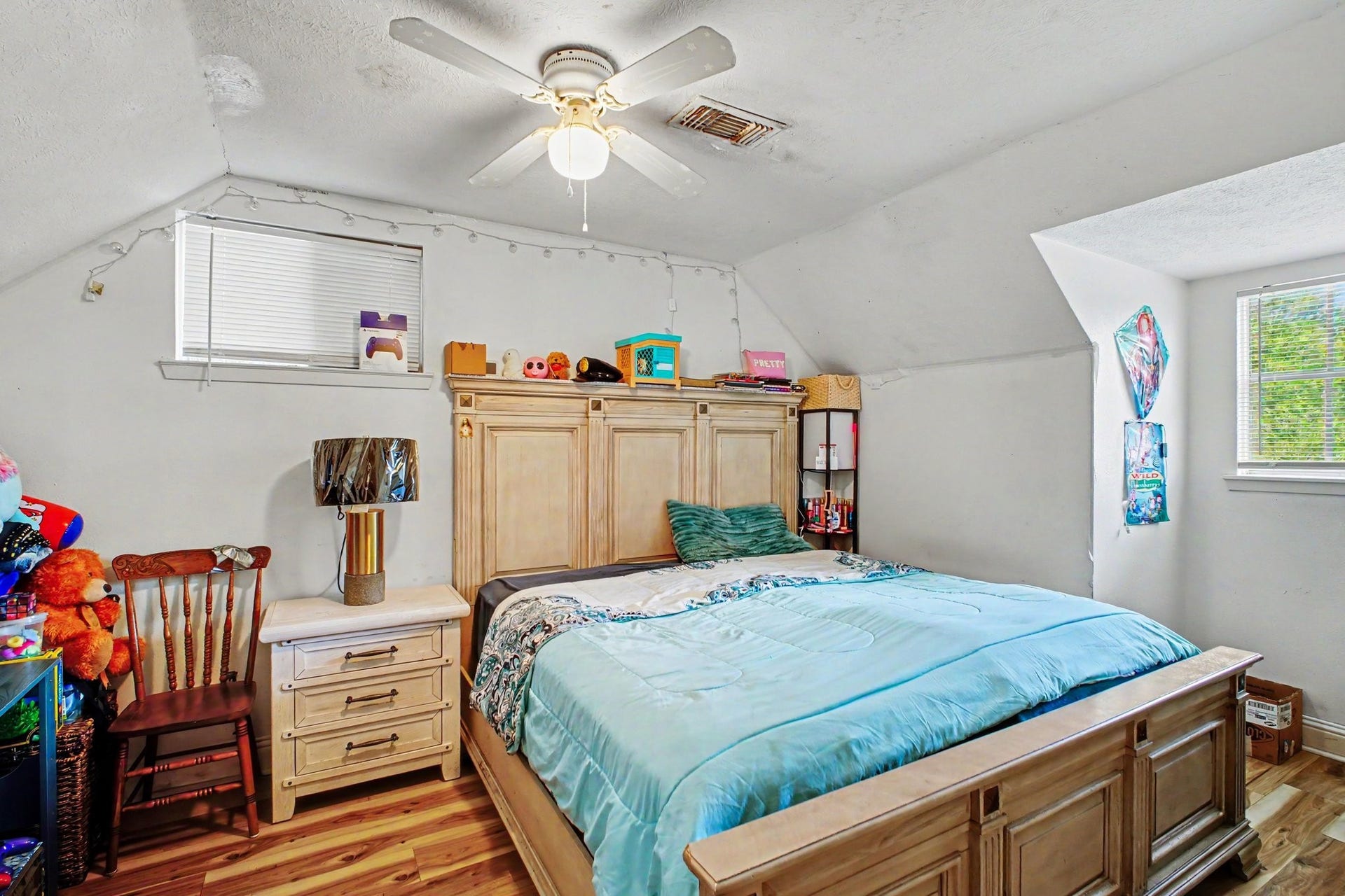 Spacious bedroom layout featuring bright windows, cozy furnishings, and an overhead ceiling fan.