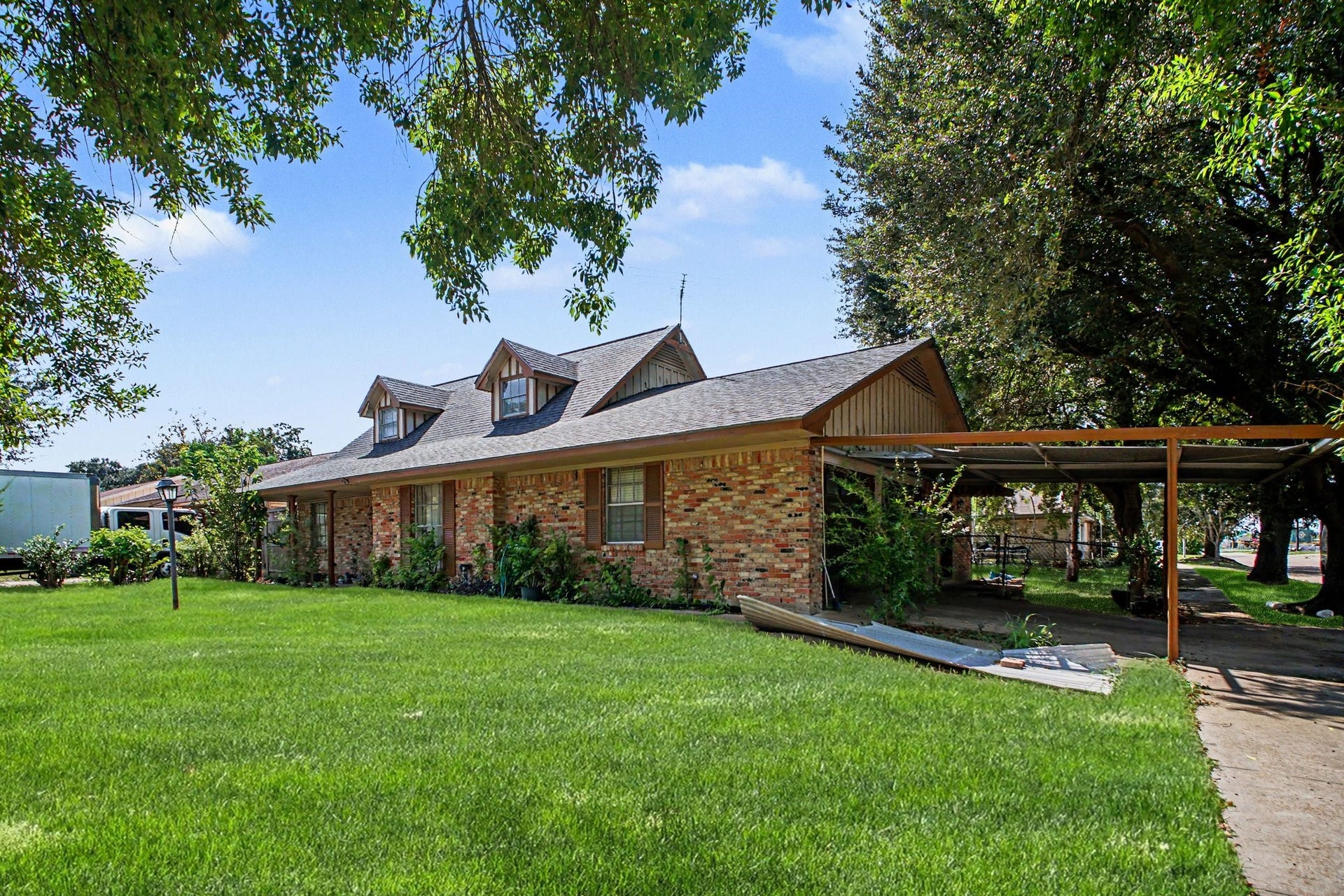 Spacious backyard area featuring a covered patio structure and open green lawn.
