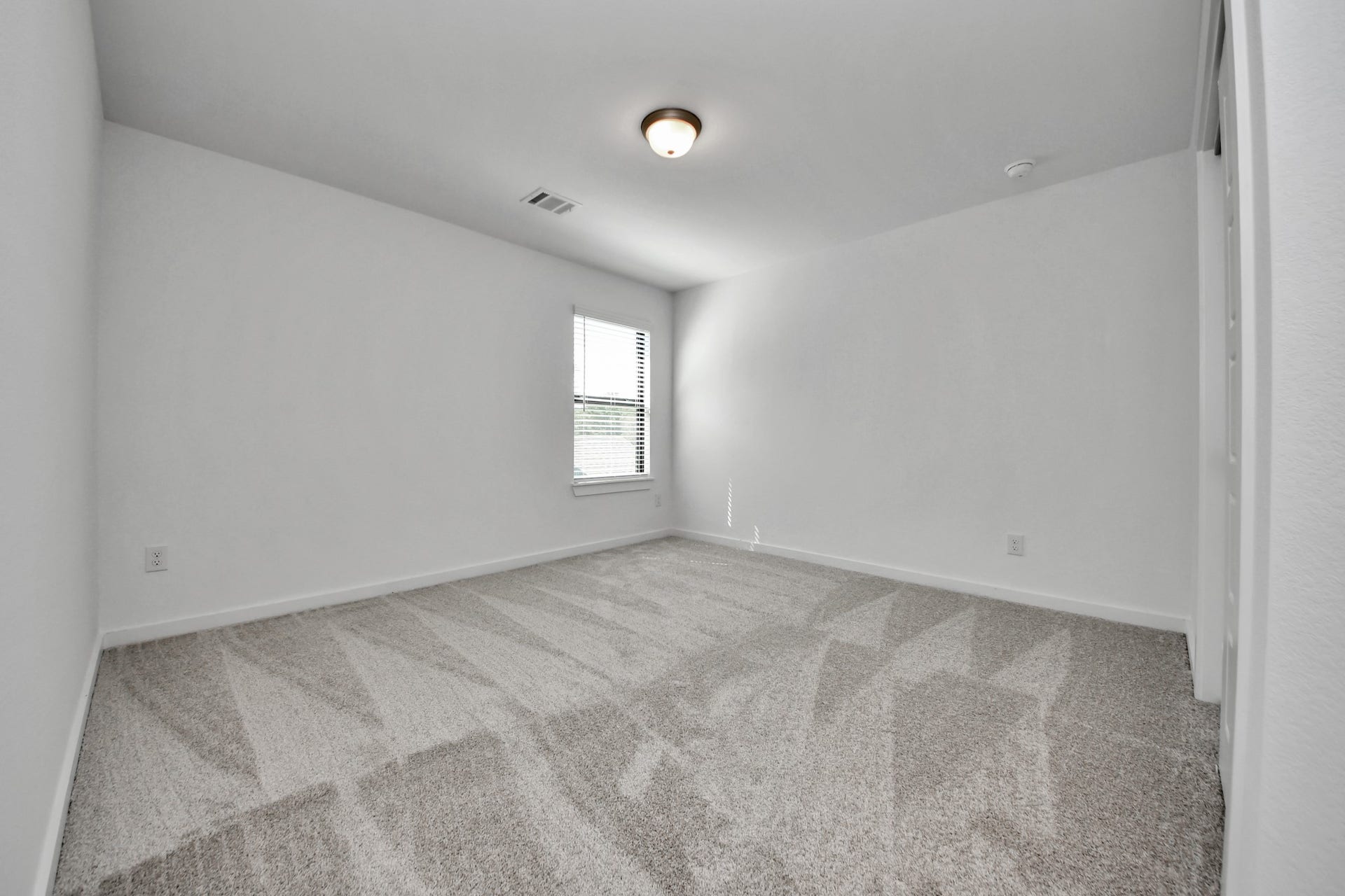Secondary bedroom features plush carpeting, large windows that let in plenty of natural light, bright paint, and spacious closets.