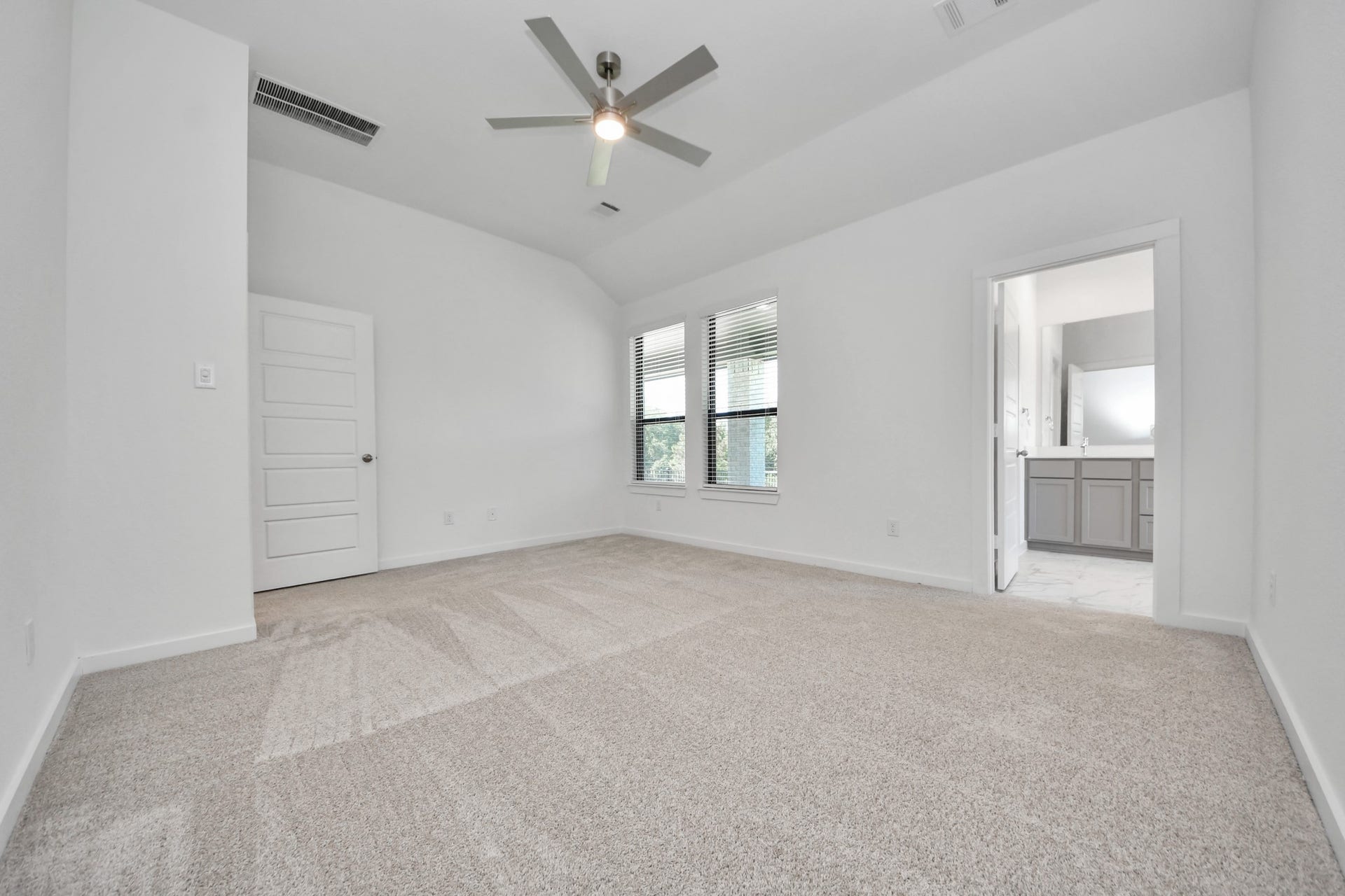 Retreat to the luxurious primary suite, your perfect escape for unwinding after a long day. Located on the first floor, this spacious room features plush carpeting, calming paint tones, high ceilings, and large windows with privacy blinds.