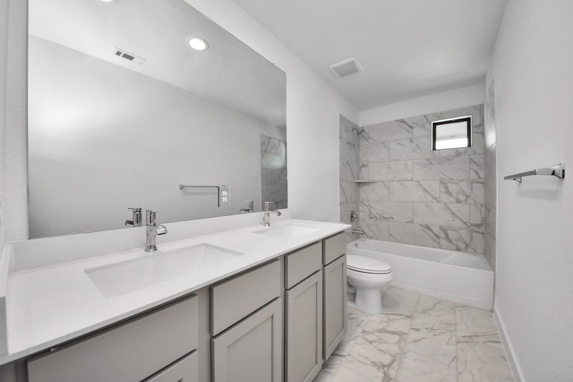 Secondary bath features tile flooring, bath/shower combo with tile surround, light stained wood cabinets, beautiful light countertop.