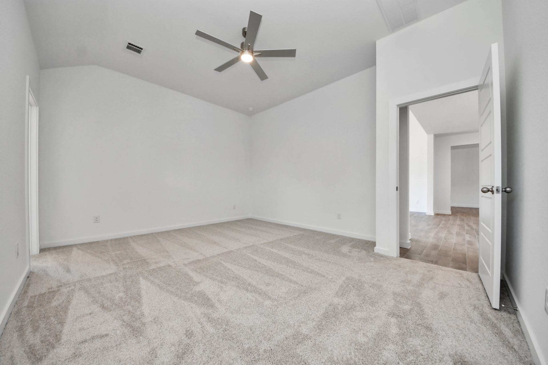 Escape and relax in the exquisite primary suite, a haven to unwind after a long day. The spacious room, located on first floor, boasts plush carpeting, soothing paint tones, high ceilings, and expansive windows adorned with privacy blinds.