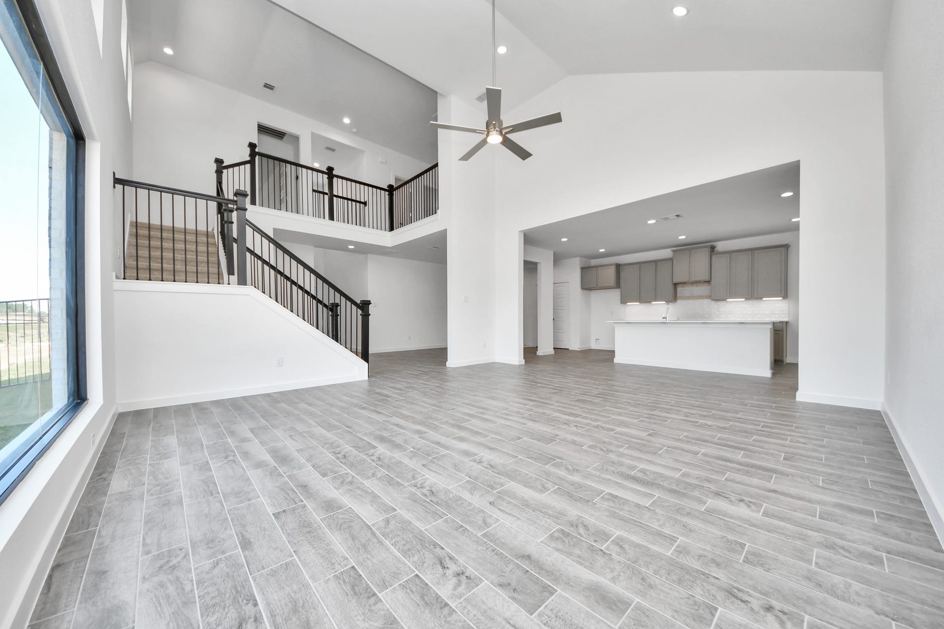 Relax and unwind in this inviting family room, illuminated by abundant natural light streaming in through tall windows, complemented by high ceilings and stunning flooring. Stay comfortable year-round with the gentle breeze from the ceiling fan, creating the perfect atmosphere for family gatherings.