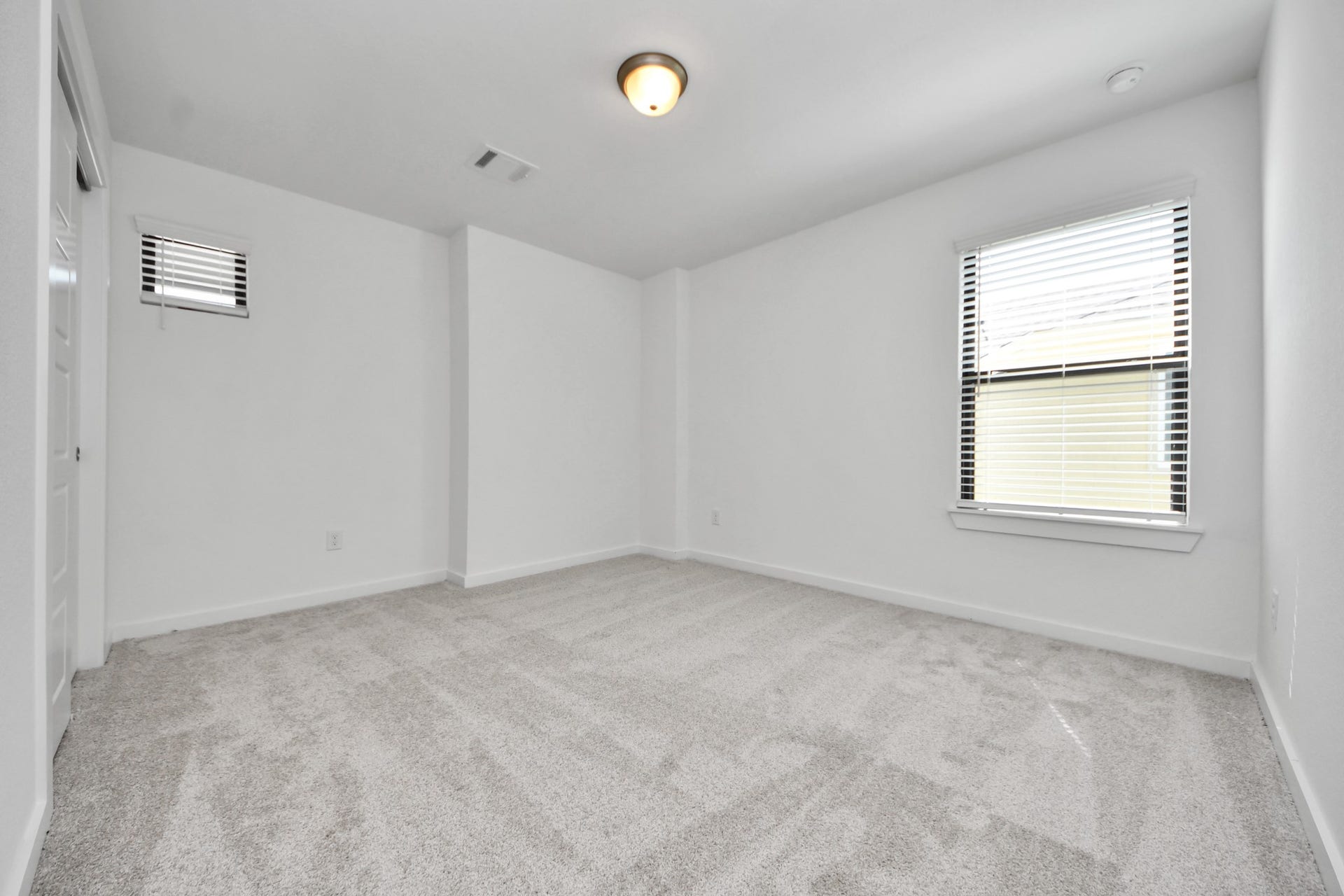 Secondary bedroom features plush carpeting, large windows that let in plenty of natural light, bright paint, and spacious closets.