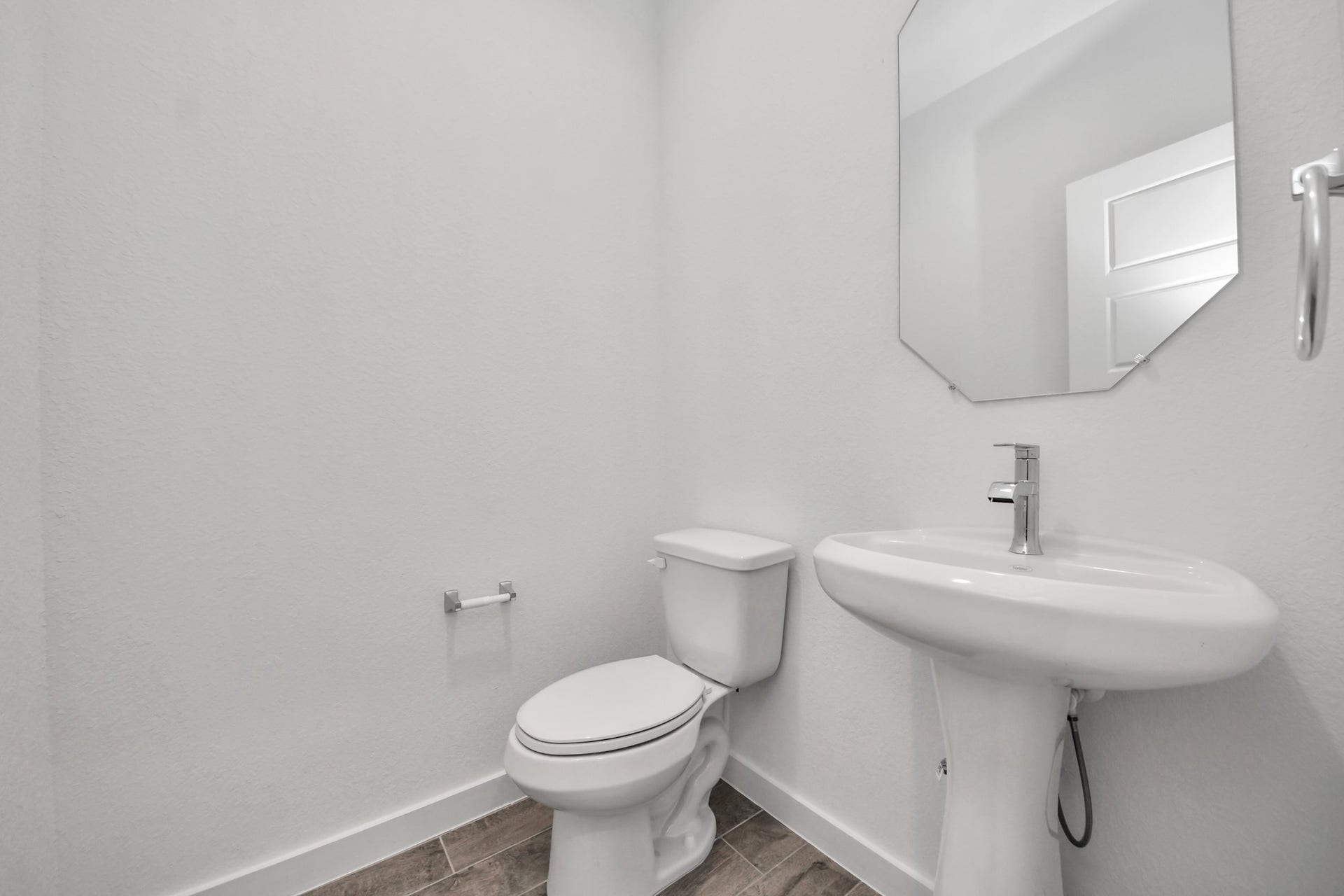 This half bathroom features a stylish pedestal sink, modern hardware, and bright recessed lighting, creating a sleek and inviting space.