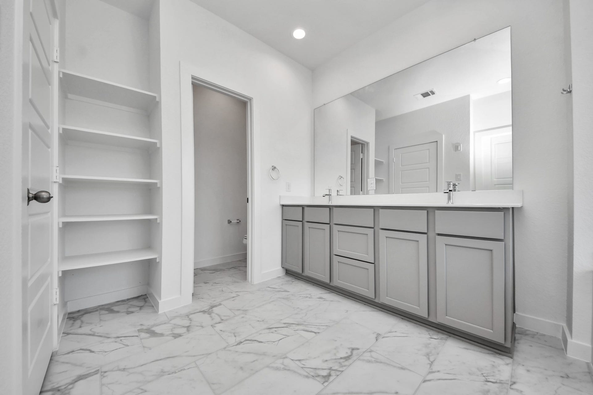 Elevate your daily routine at the elegant vanity, now equipped with double sinks, light countertops, modern hardware, and beautiful recessed lights.