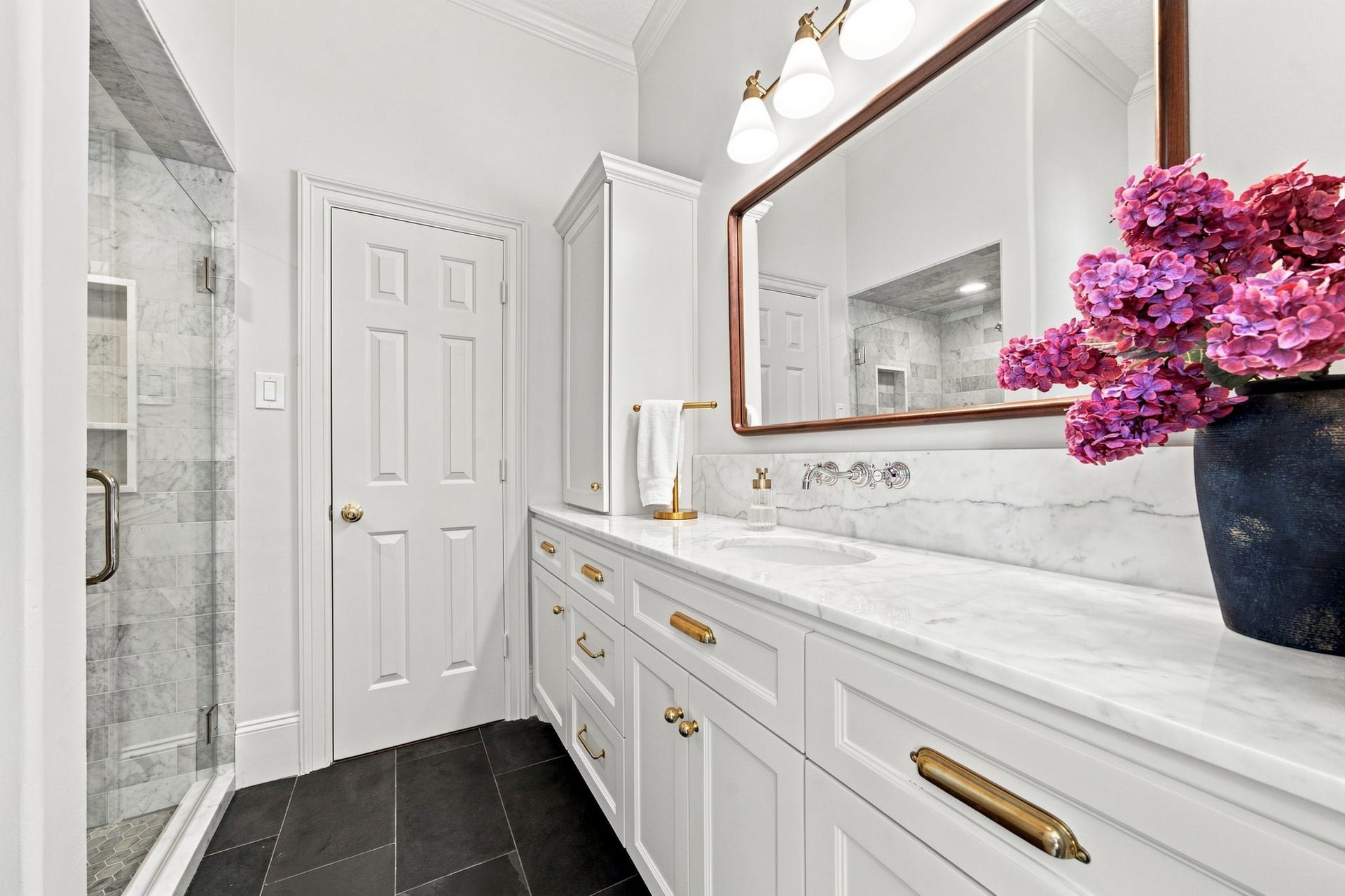 23 S Brokenfern Drive Drive, The Woodlands, TX 77380 Pool bathroom features onsite built custom cabinetry, slate flooring, carrera marble shower, and timeless chic brass hardware.