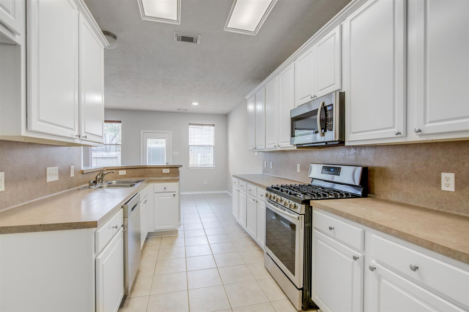 58 S Burberry Park Circle, The Woodlands, TX 77382 Spacious kitchen featuring sleek white cabinetry, modern stainless steel appliances, and ample countertop space, perfect for culinary enthusiasts.