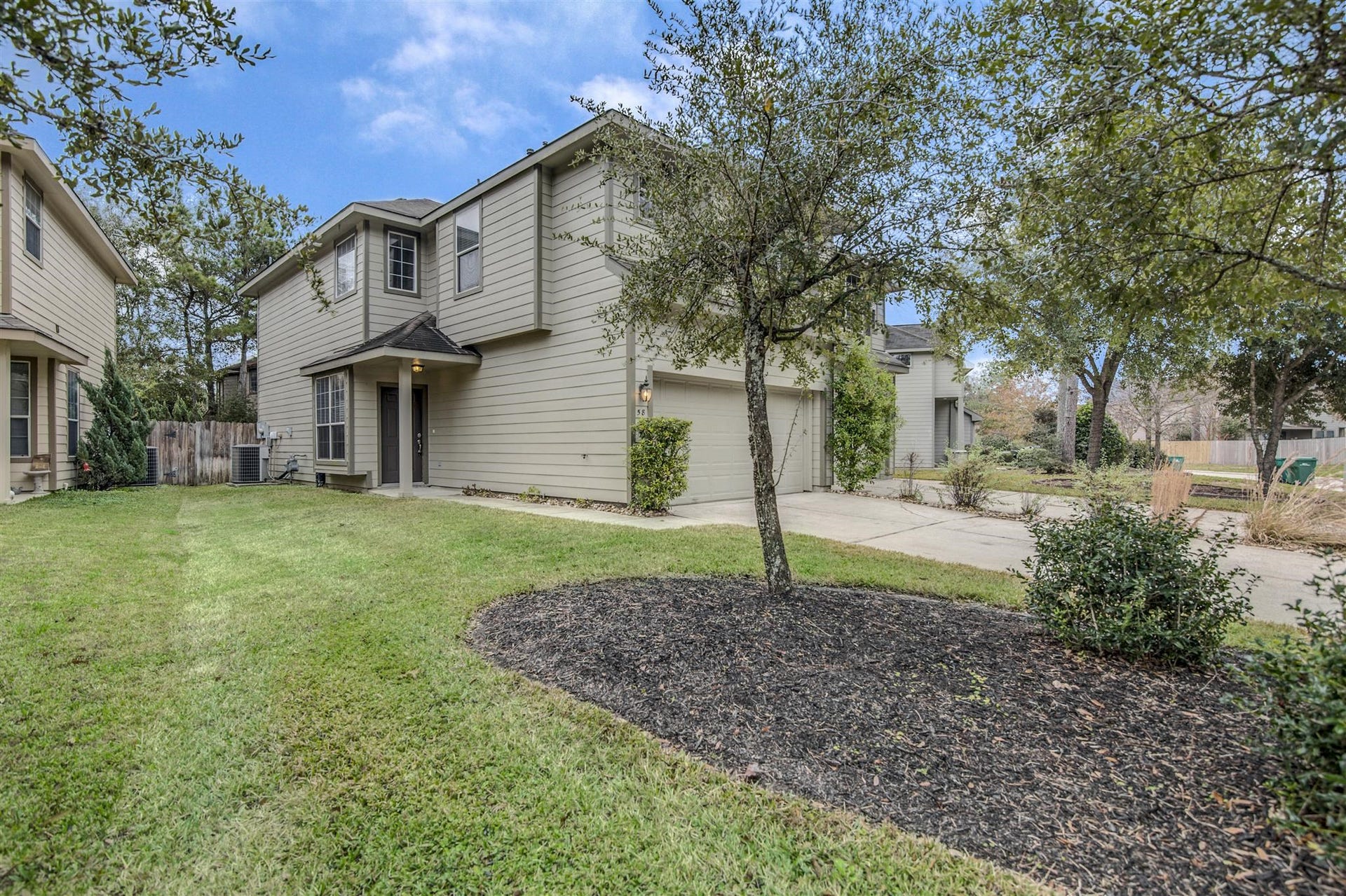 58 S Burberry Park Circle, The Woodlands, TX 77382 Charming two-story home with a welcoming front entrance, attached garage, and a spacious, well-maintained lawn surrounded by mature trees.