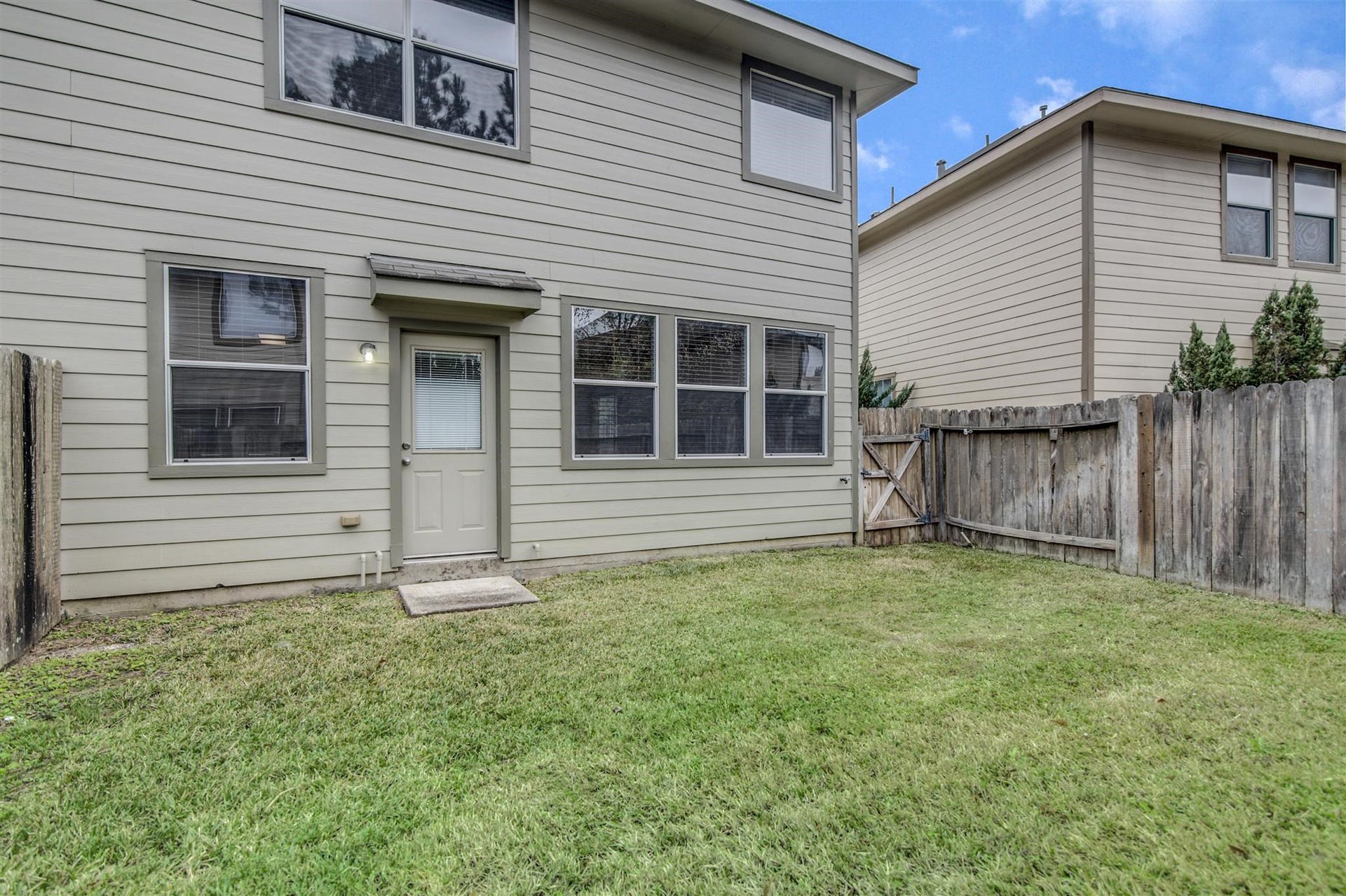 58 S Burberry Park Circle, The Woodlands, TX 77382 Charming backyard space with a well-maintained lawn, perfect for outdoor activities, framed by a wooden fence for privacy.