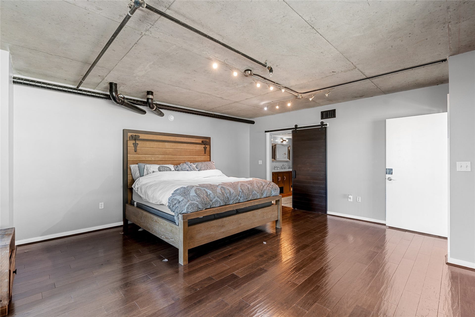 2000 Bagby St Street, #13430, Houston, TX 77002 The spacious primary bedroom occupies the upper level, pairing warm wood flooring with exposed concrete ceilings for a refined take on the lofts industrial character.
