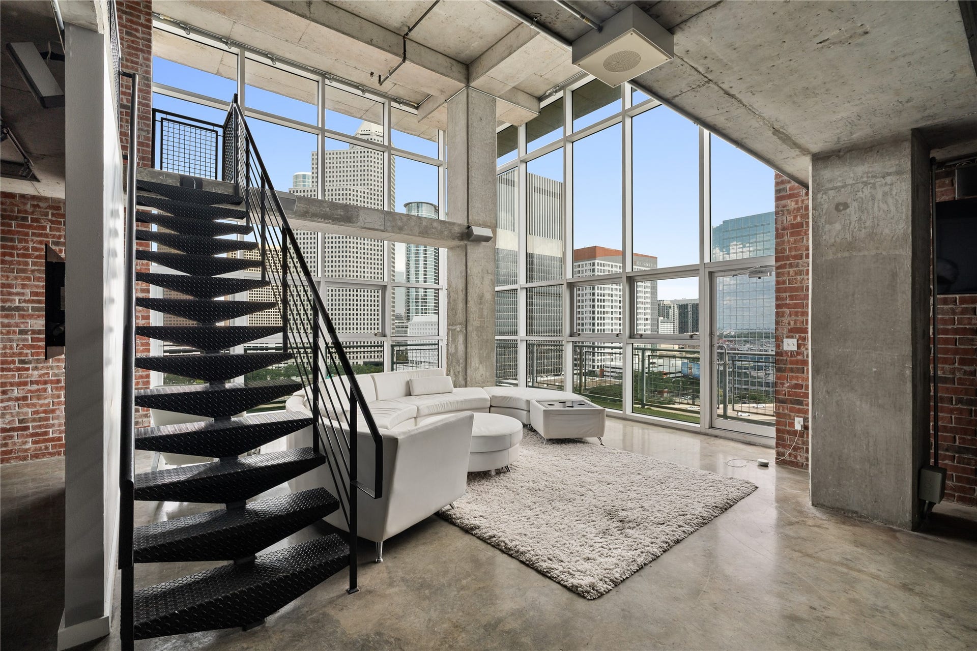 2000 Bagby St Street, #13430, Houston, TX 77002 Soaring floor to ceiling windows flood the two story living area with natural light, while the open metal staircase reinforces the lofts dramatic industrial character.