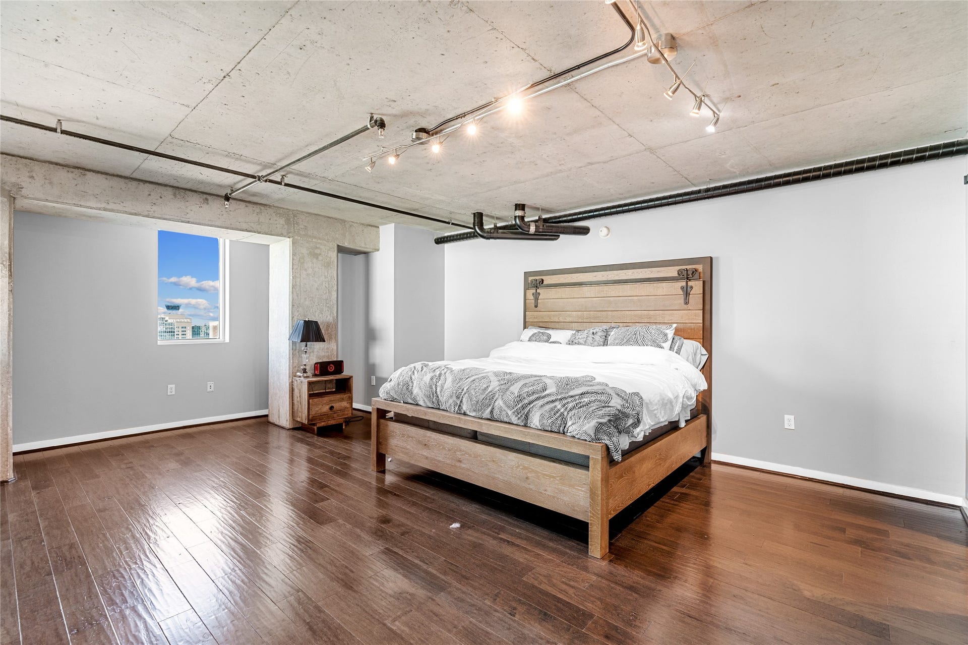 2000 Bagby St Street, #13430, Houston, TX 77002 Another perspective of the expansive primary suite highlights generous proportions, warm wood flooring and exposed concrete ceilings, leaving ample room for a private sitting area.