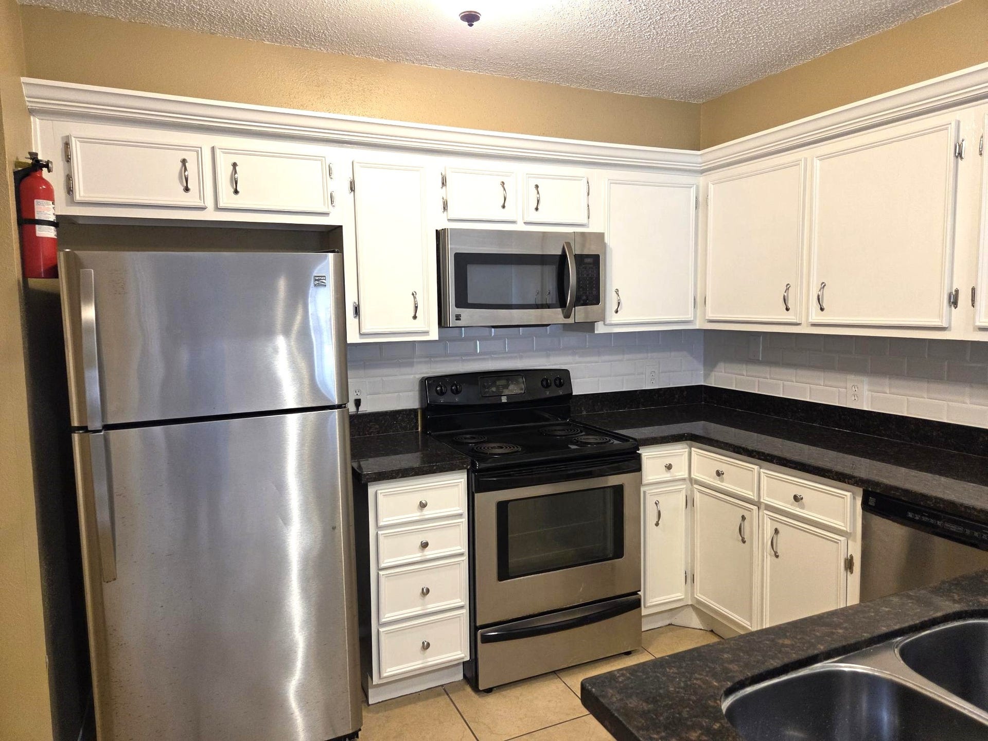 Bright Kitchen with cabinet storage, stove, microwave, refrigerator and double sinks. Nicely accented by granite countertops.