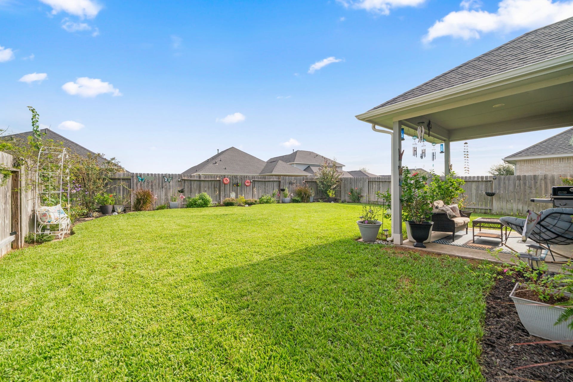 31410 Whitfield Court, Fulshear, TX 77441 Expansive backyard with lush green lawn, perfect for outdoor activities and relaxation. The covered patio offers a cozy seating area, ideal for entertaining or enjoying peaceful evenings.