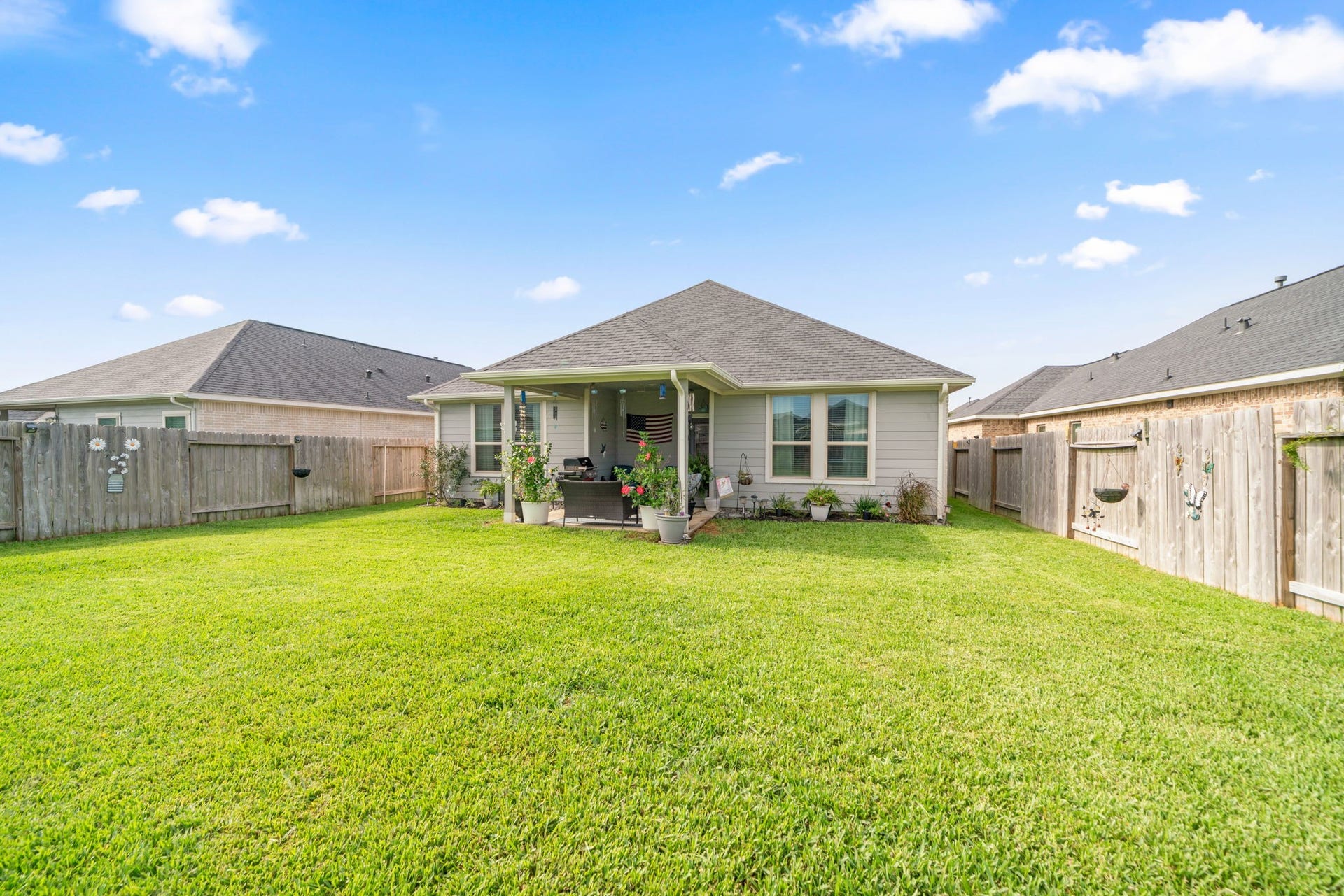31410 Whitfield Court, Fulshear, TX 77441 Charming backyard with lush green lawn, cozy patio area, and privacy fencing, perfect for outdoor relaxation and gatherings.