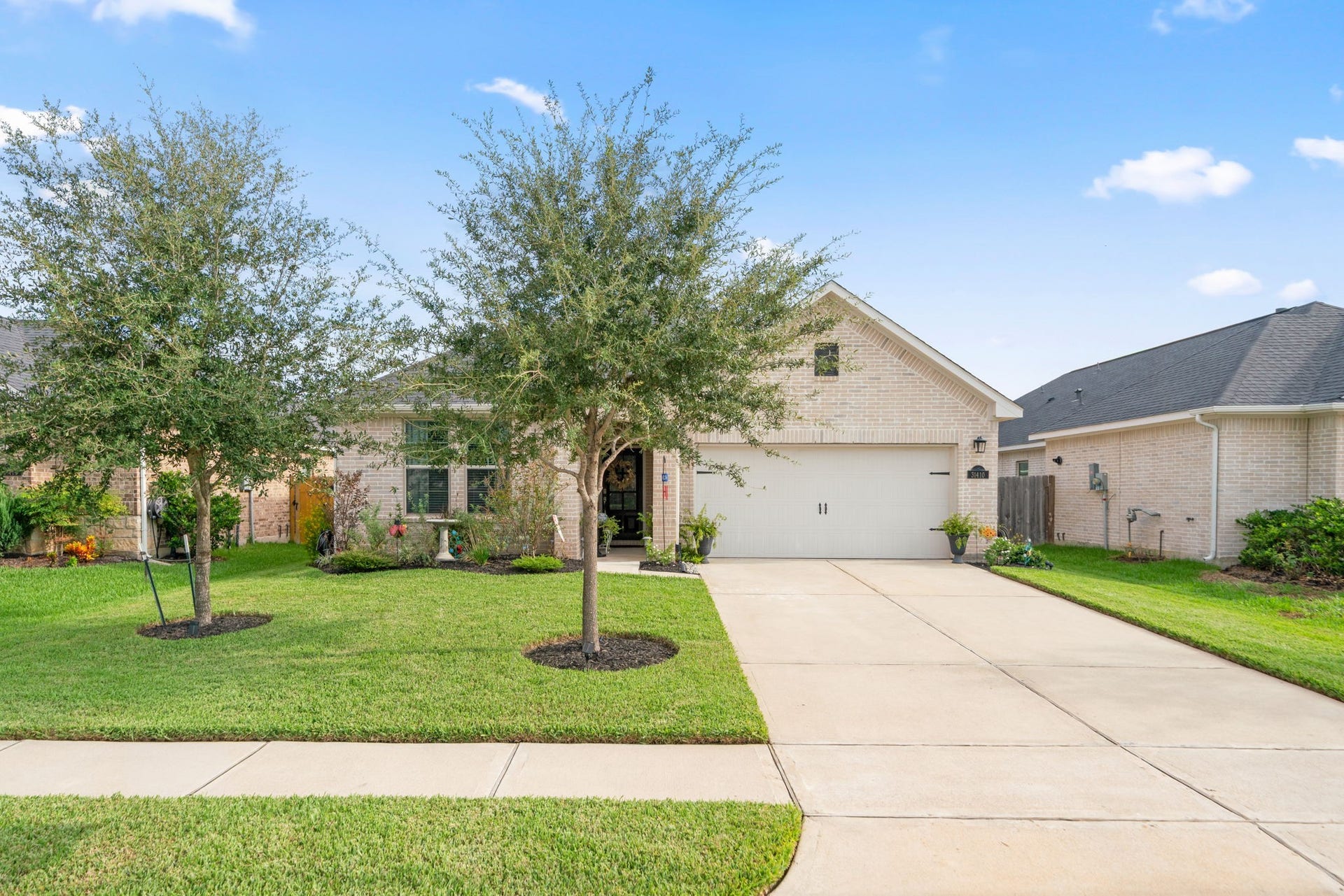 31410 Whitfield Court, Fulshear, TX 77441 Charming single-story home with a beautifully manicured lawn and a spacious driveway leading to a two-car garage.