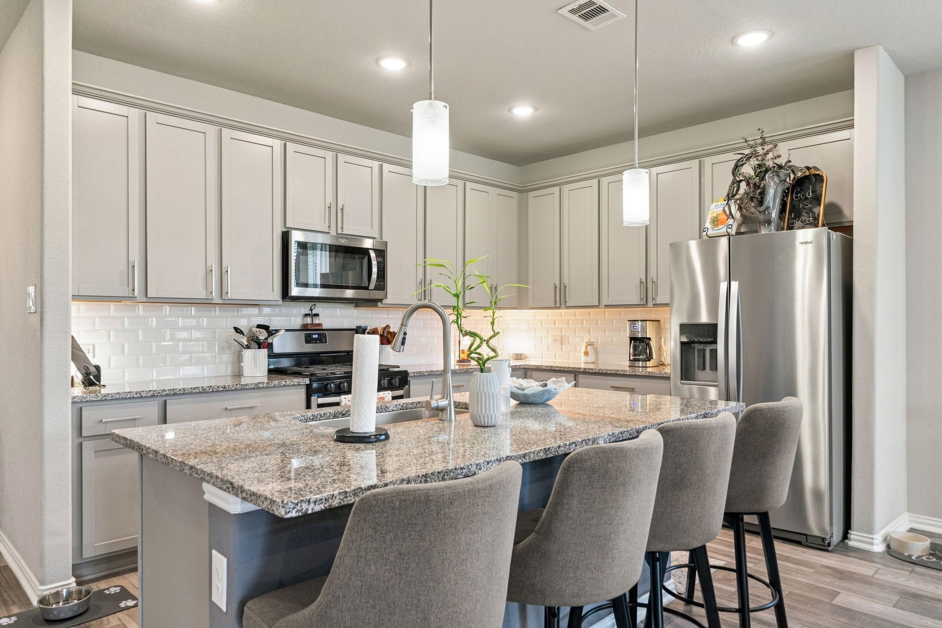 31410 Whitfield Court, Fulshear, TX 77441 Modern kitchen with sleek granite countertops, stainless steel appliances, and ample cabinetry, complemented by a stylish island with seating for four.
