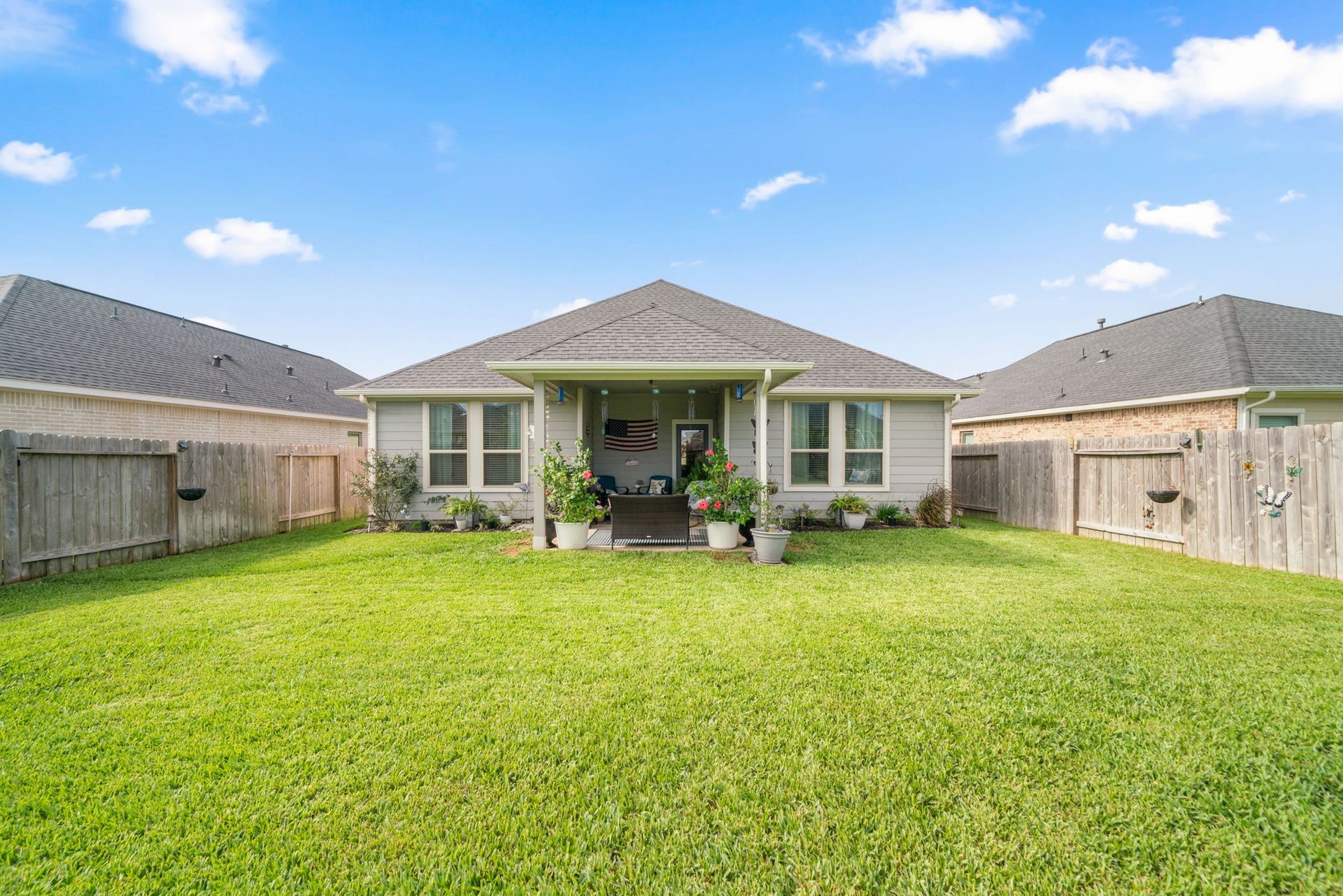 31410 Whitfield Court, Fulshear, TX 77441 Charming backyard oasis with a lush green lawn, cozy covered patio, and vibrant garden beds, perfect for outdoor relaxation and entertainment.