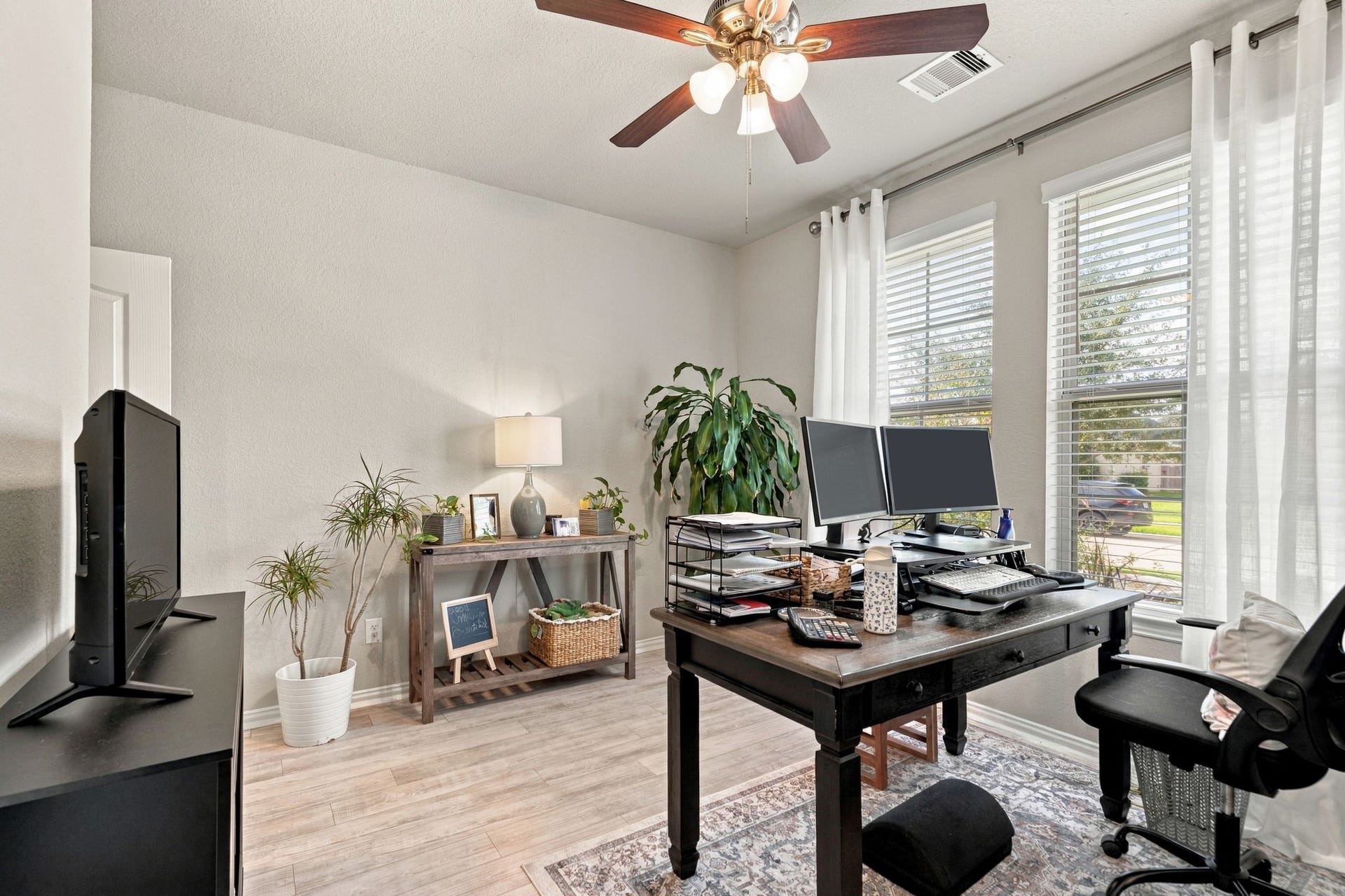 31410 Whitfield Court, Fulshear, TX 77441 Home office features large windows for natural light, a ceiling fan, and stylish wood flooring, creating an ideal workspace.