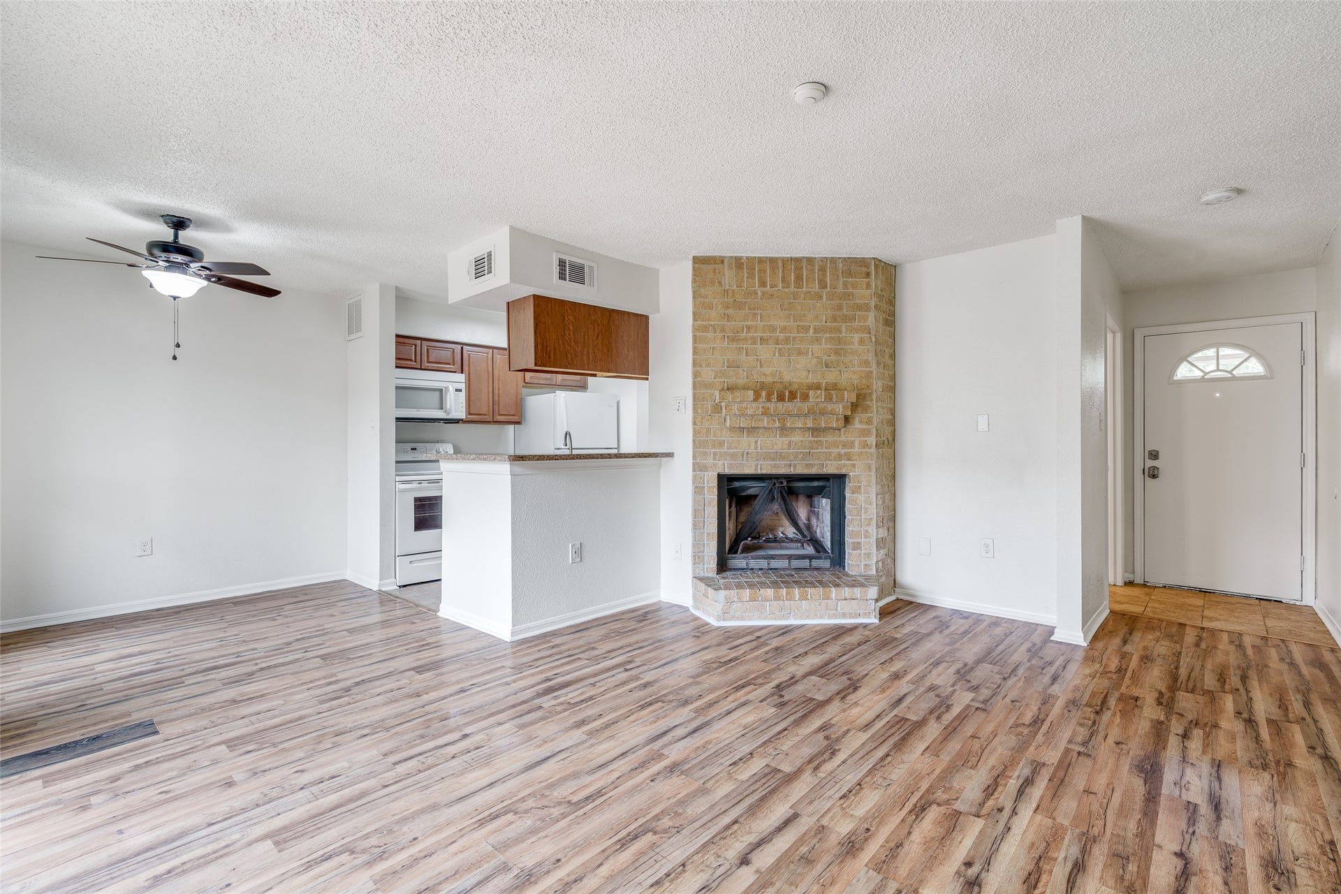 250 El Dorado Boulevard, #283, Houston, TX 77598 The living room features stylish flooring, a ceiling fan for comfort, and a charming brick wood-burning fireplace that adds warmth and character to the space.