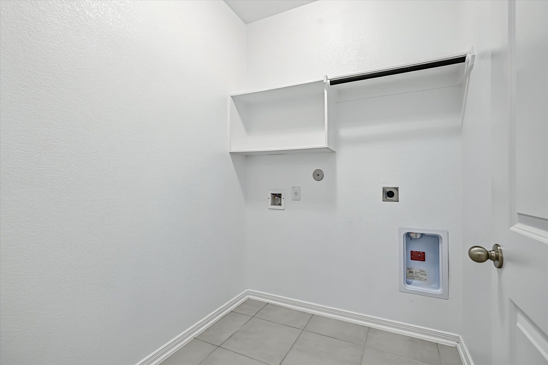 9607 Bright Song Lane, Houston, TX 77078 Spacious laundry room with hookups, shelving, and tile flooring, offering excellent functionality for your home.