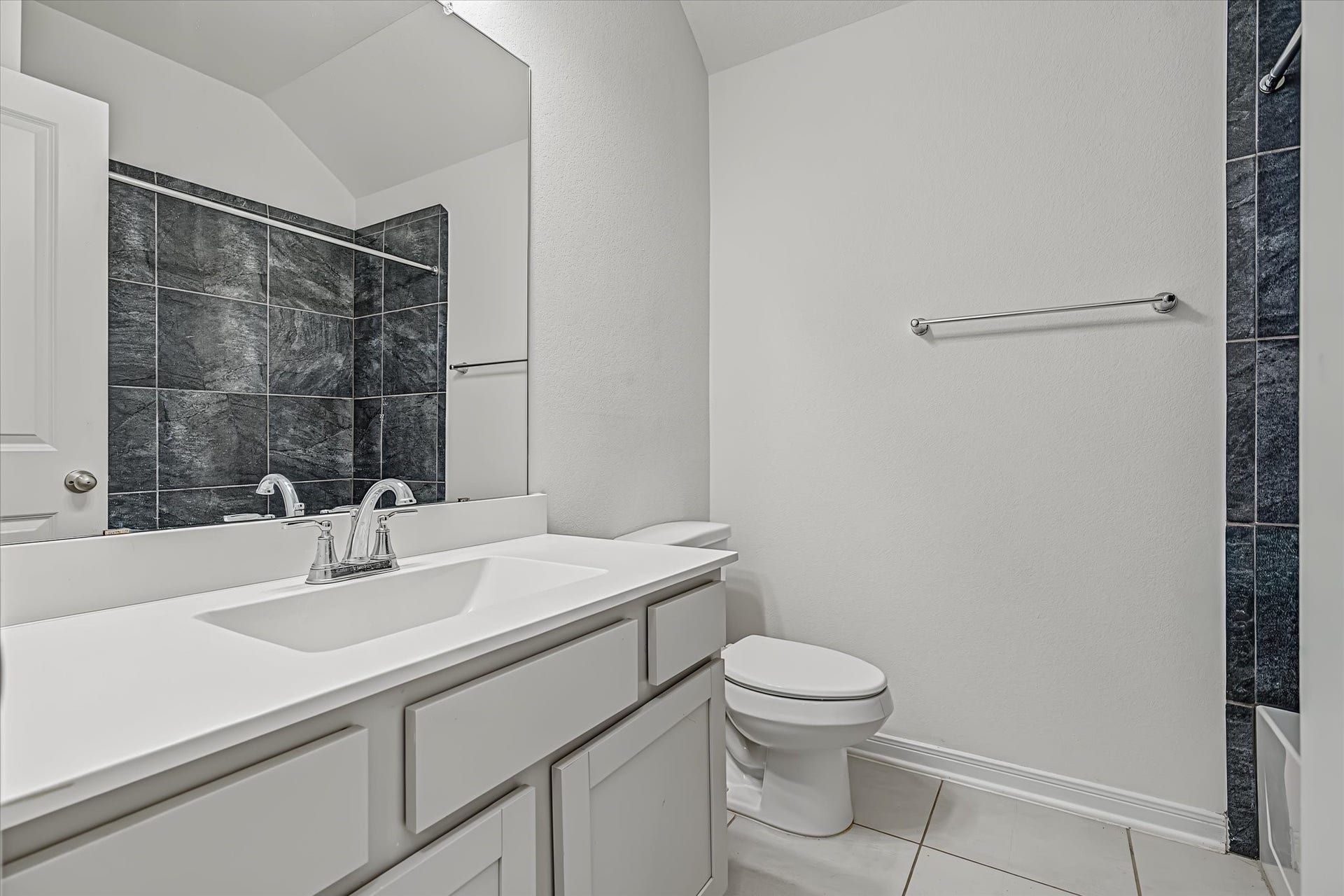 9607 Bright Song Lane, Houston, TX 77078 Sleek 2nd bathroom featuring a modern vanity with ample storage, elegant black tile accents, and a clean, minimalist design.