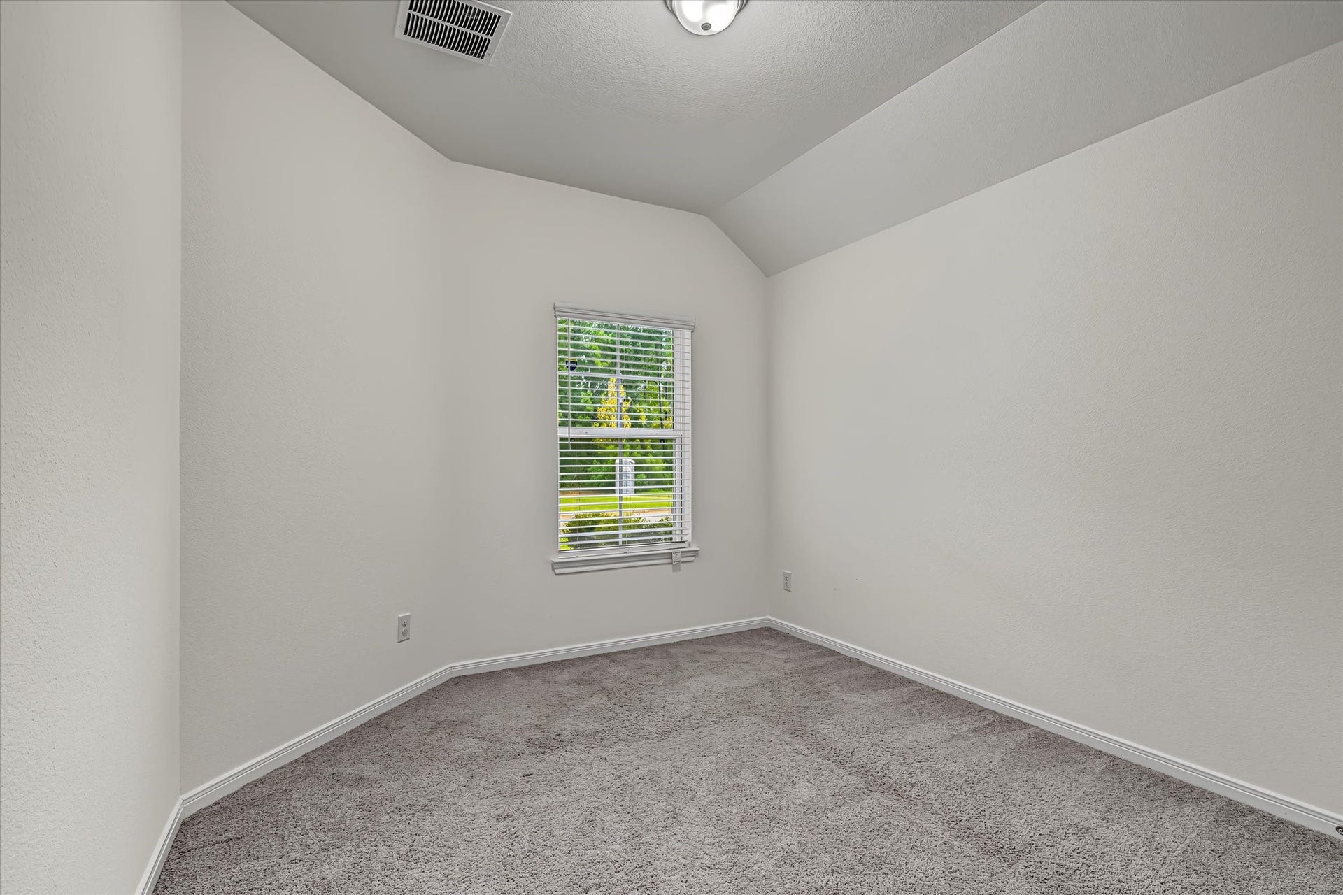 9607 Bright Song Lane, Houston, TX 77078 Cozy 2nd bedroom with plush carpeting, soft neutral walls, and a window providing natural light and a view of the greenery outside.