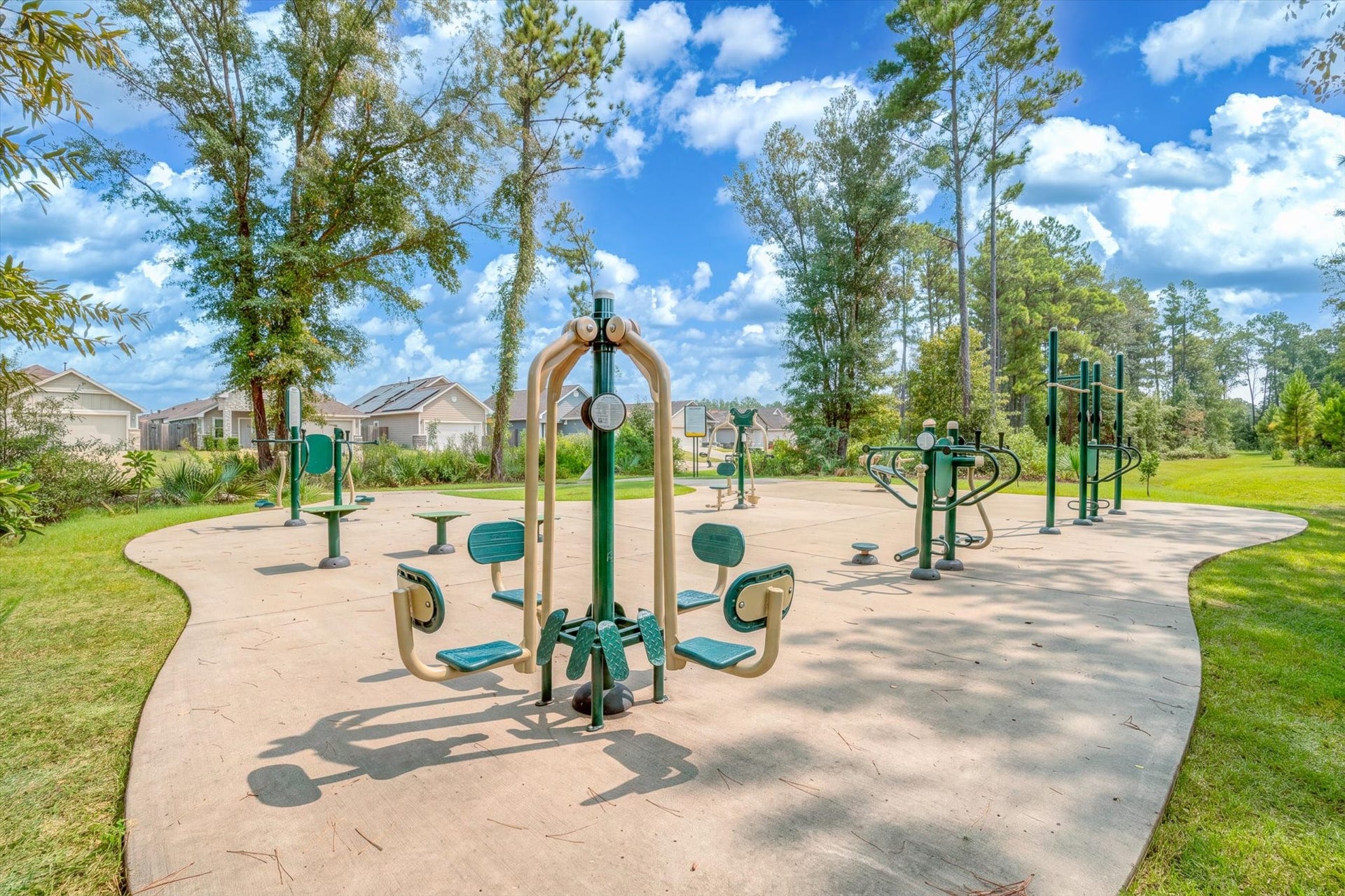 9607 Bright Song Lane, Houston, TX 77078 Outdoor fitness area surrounded by lush greenery, offering a variety of exercise equipment in a serene community setting.