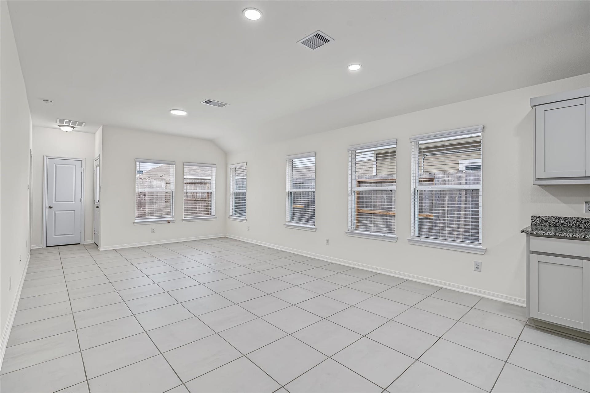 9607 Bright Song Lane, Houston, TX 77078 Spacious, light-filled Den & Dining Combo with large windows and sleek tile flooring, perfect for versatile living arrangements.